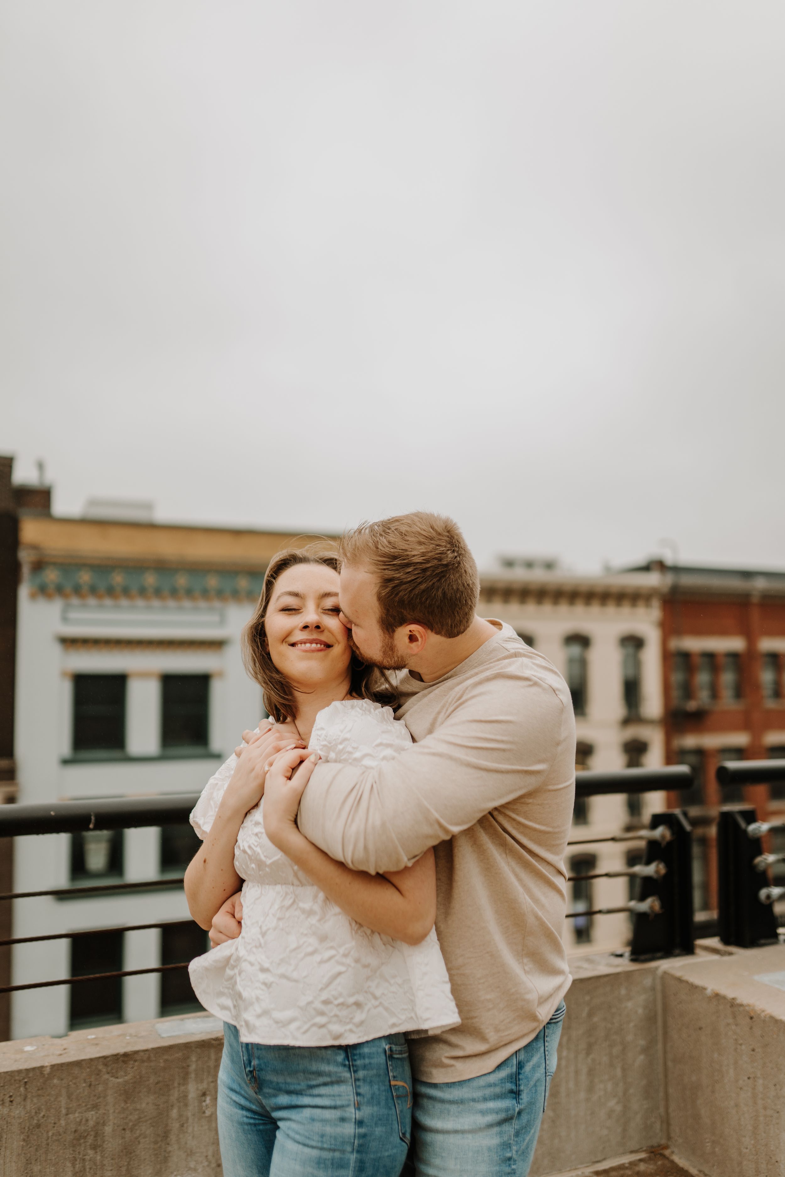 Casual couple photography session with natural laughter and embraces on city rooftop.