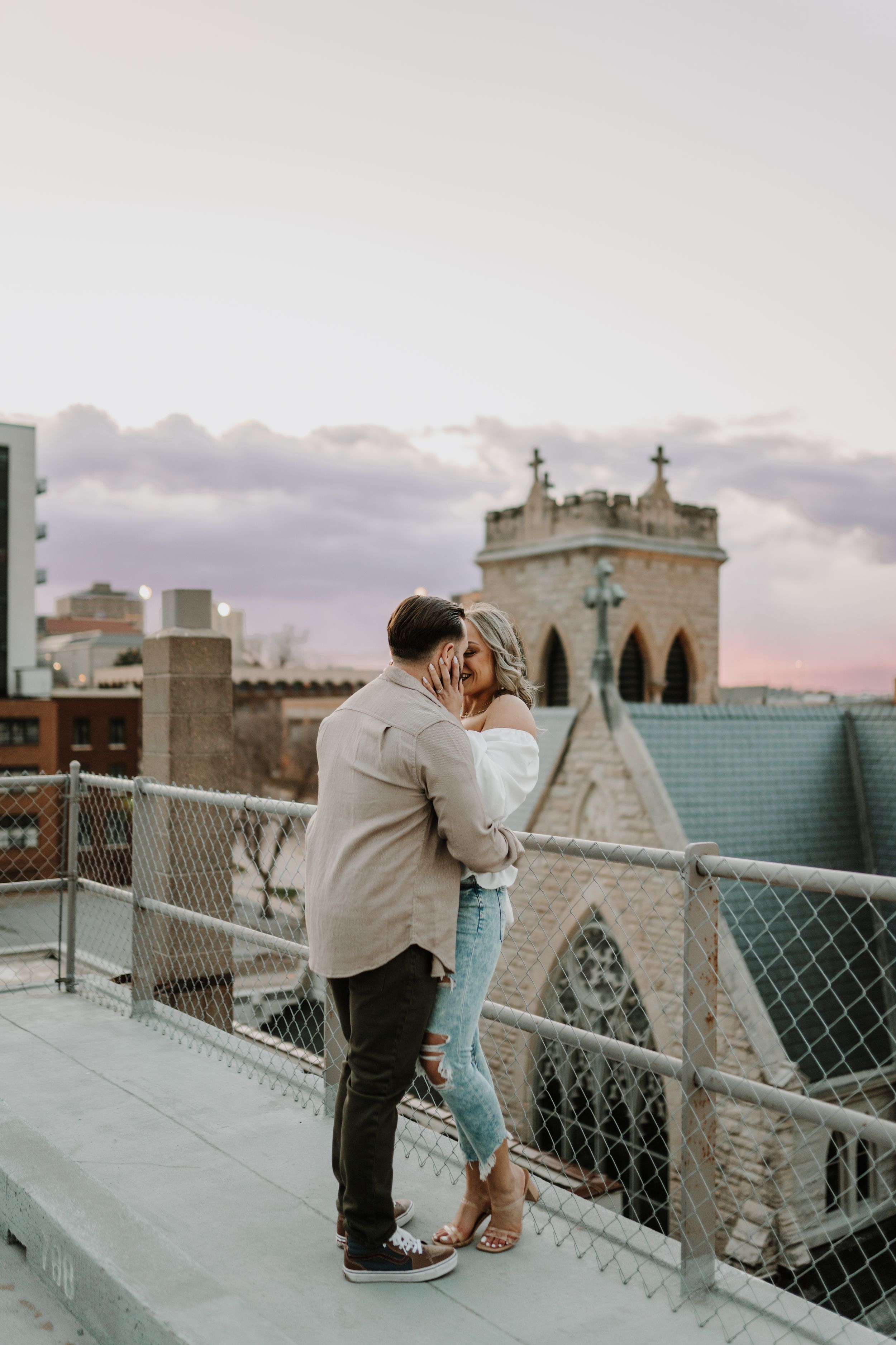 Romantic engagement photos taken on a bridge with architectural details at sunset.