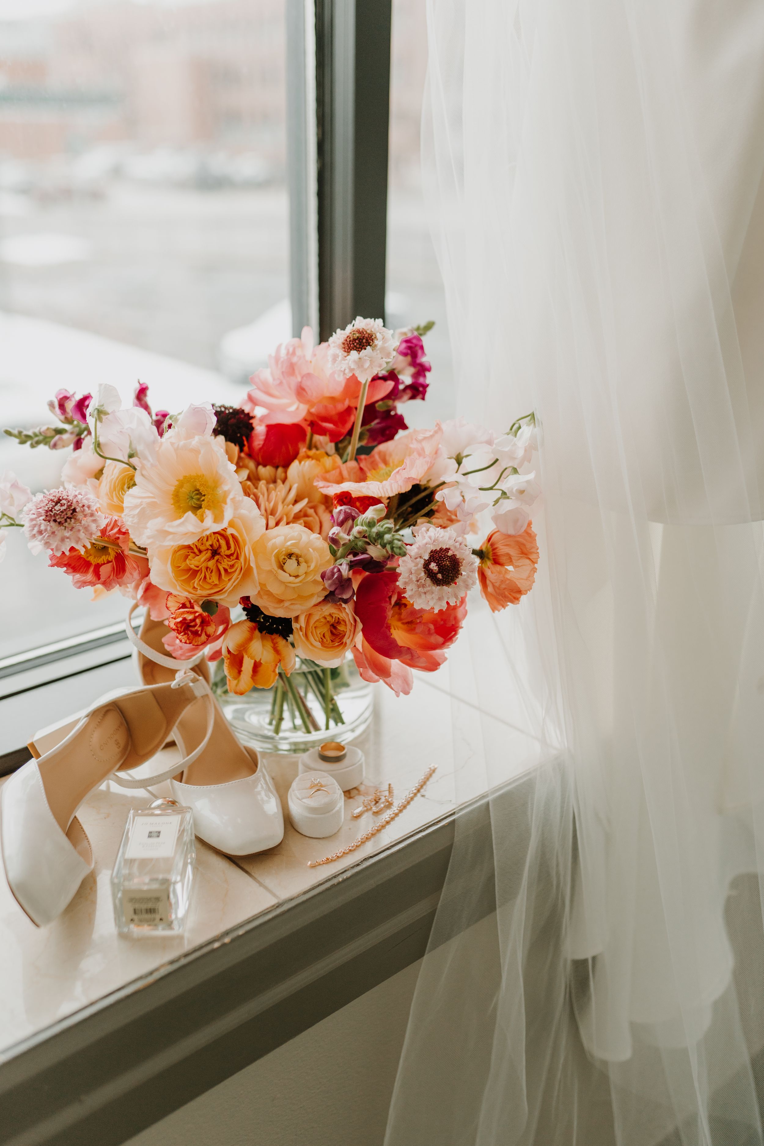 Colorful floral arrangements with pink and orange blooms displayed on a windowsill.
