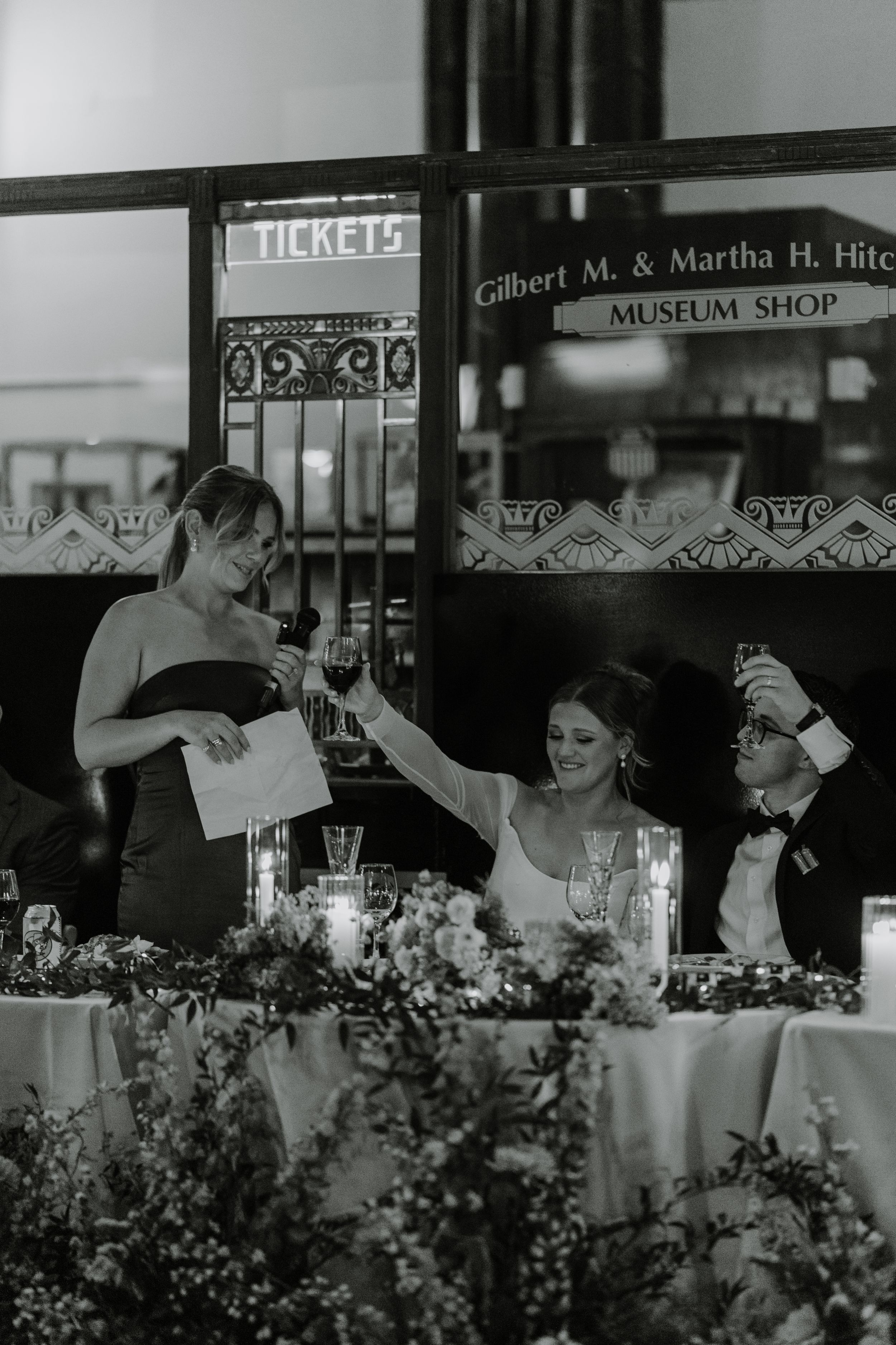 Black and white photo of wedding reception with guests being served at an elegant dinner table.