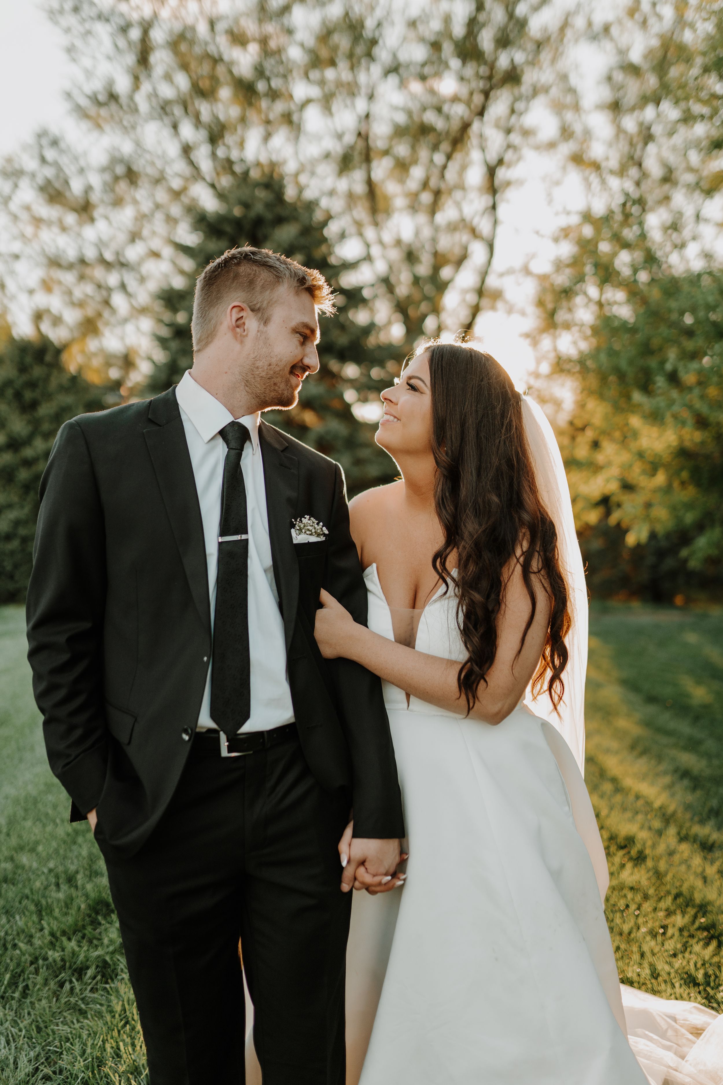 Romantic wedding photo of couple sharing a tender moment outdoors at golden hour.