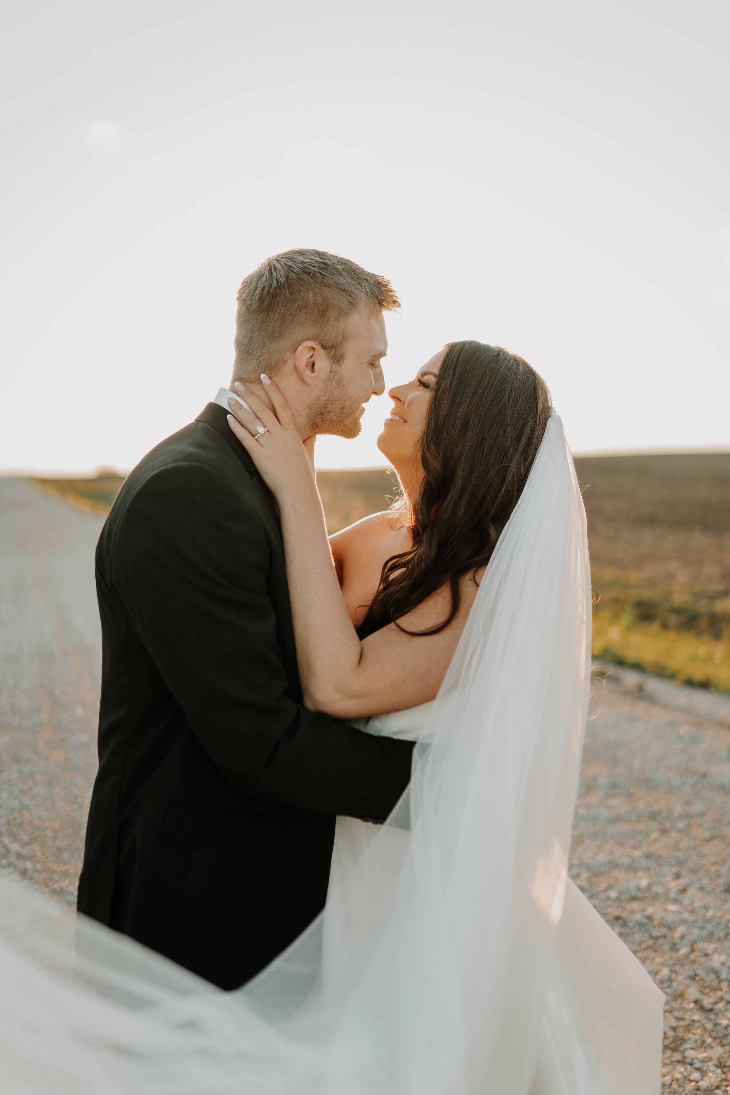 Romantic close-up of bride and groom embracing against sunset backdrop.
