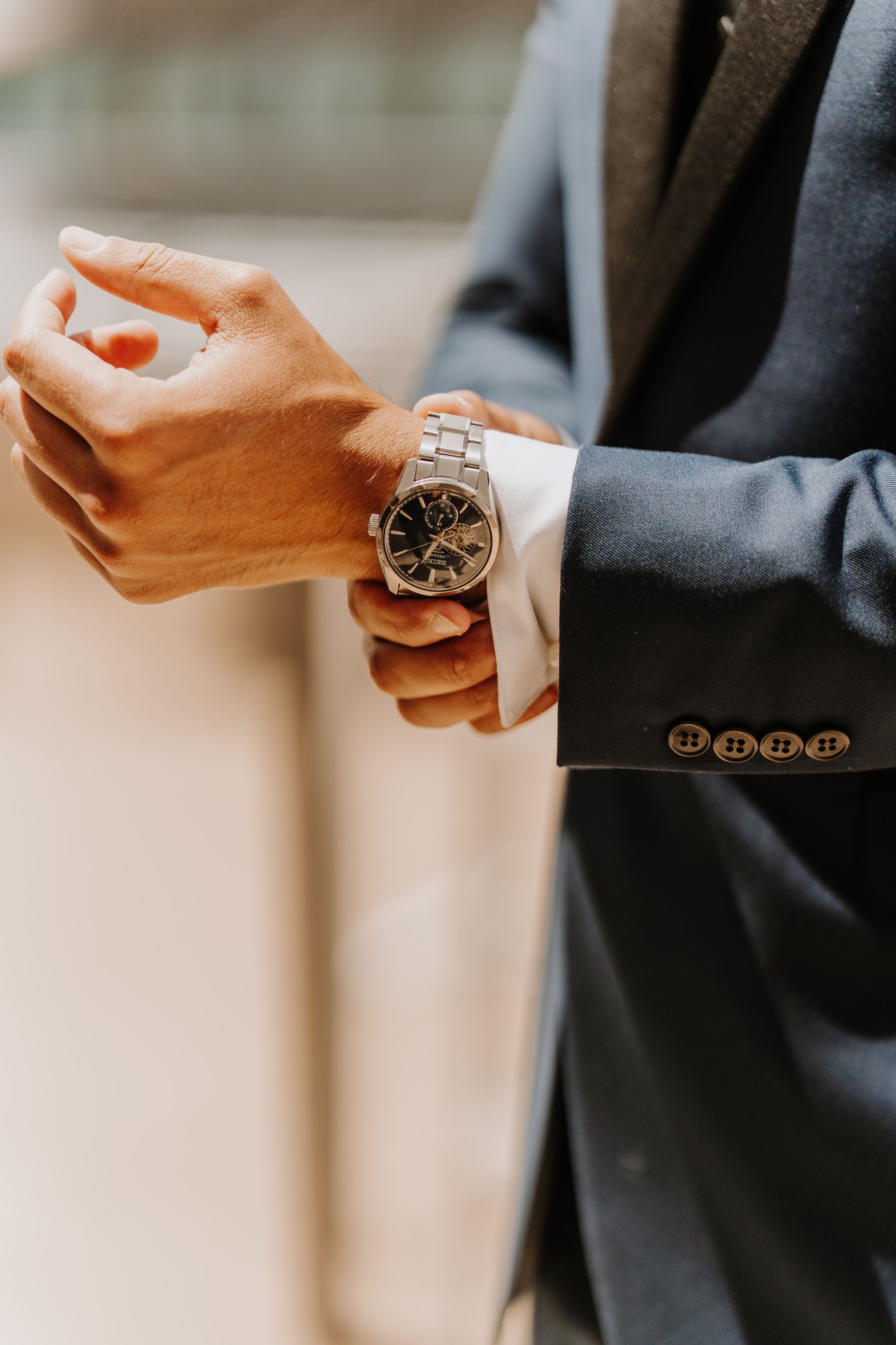 Person in a suit checking their wristwatch with warm lighting.