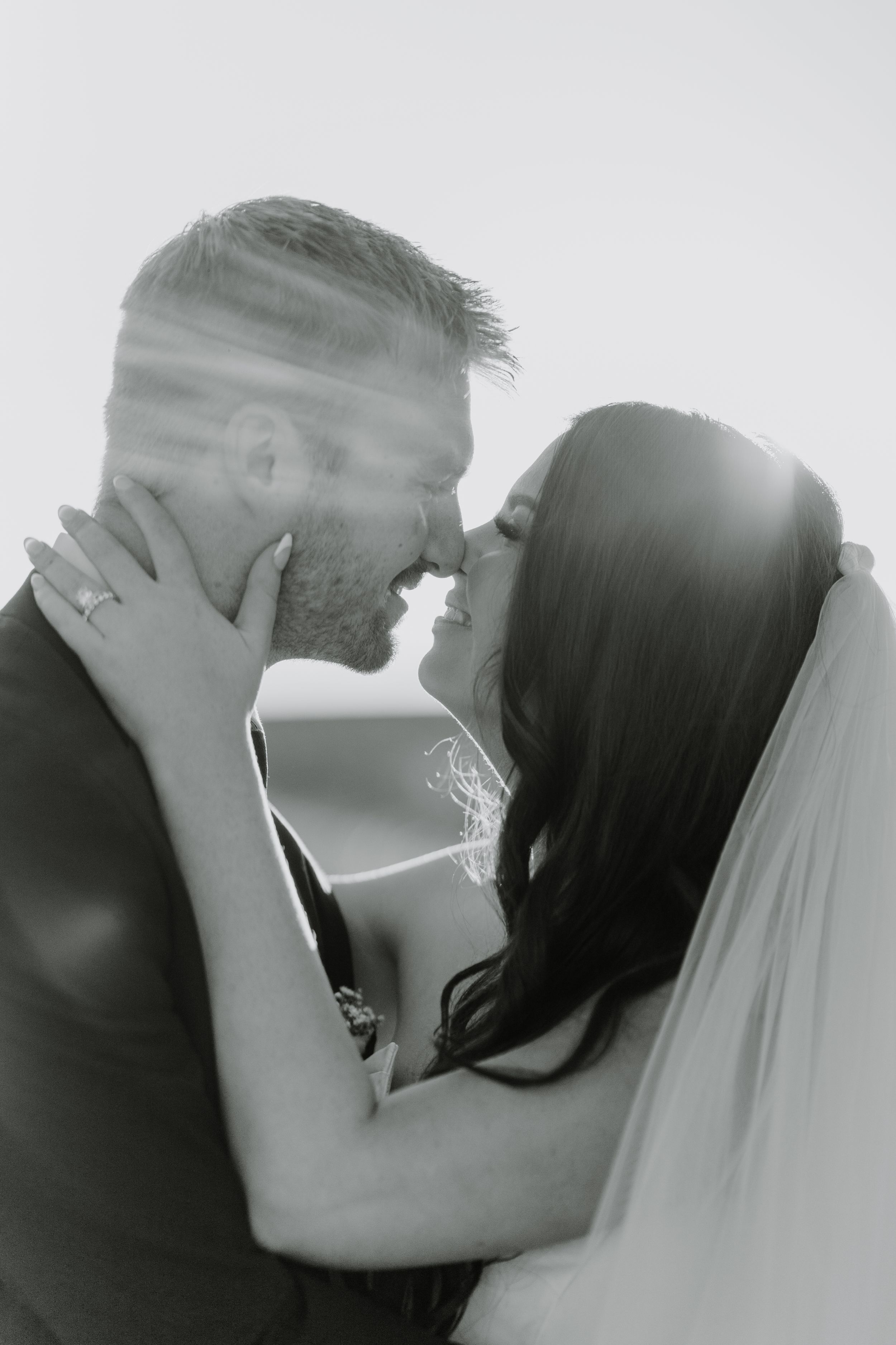 Black and white intimate portrait of newlyweds sharing romantic kiss.