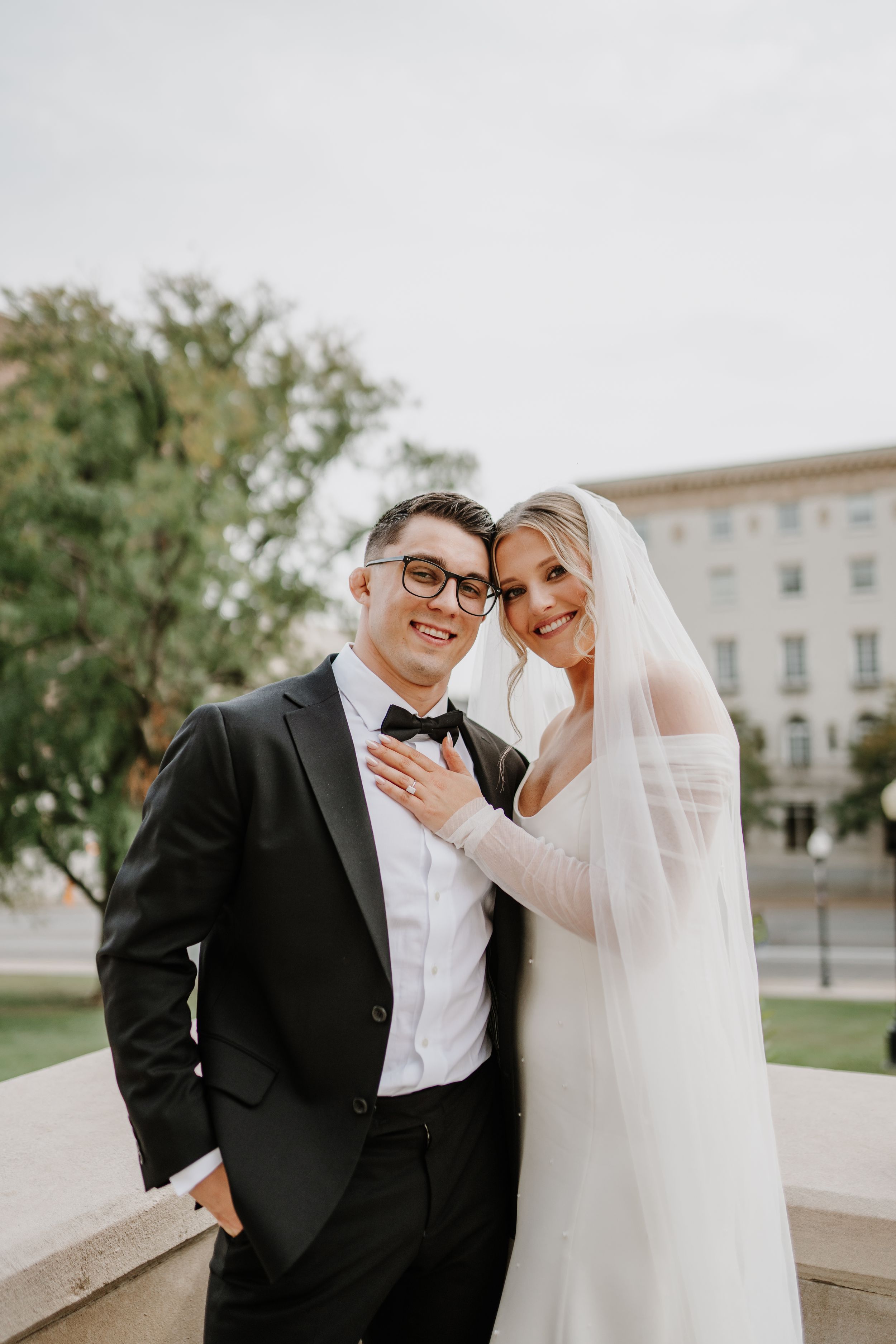Intimate wedding portrait of couple sharing tender moment on classic stone balcony.