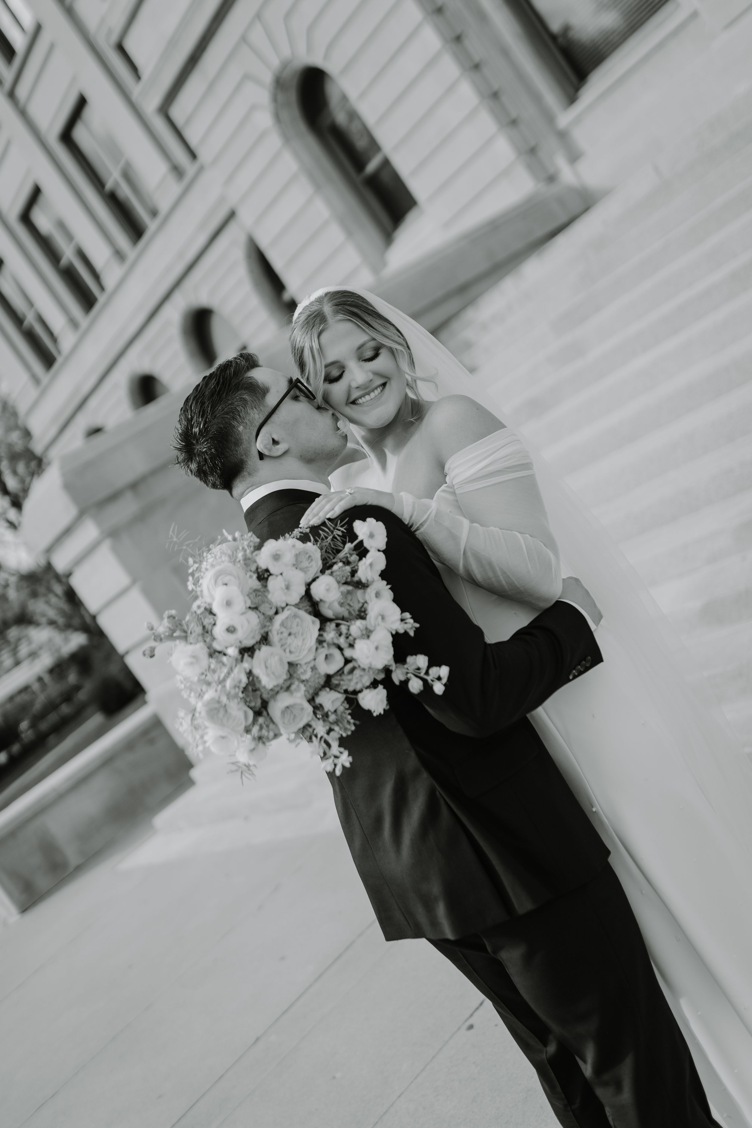 Black and white wedding photo capturing intimate moment between newlyweds.