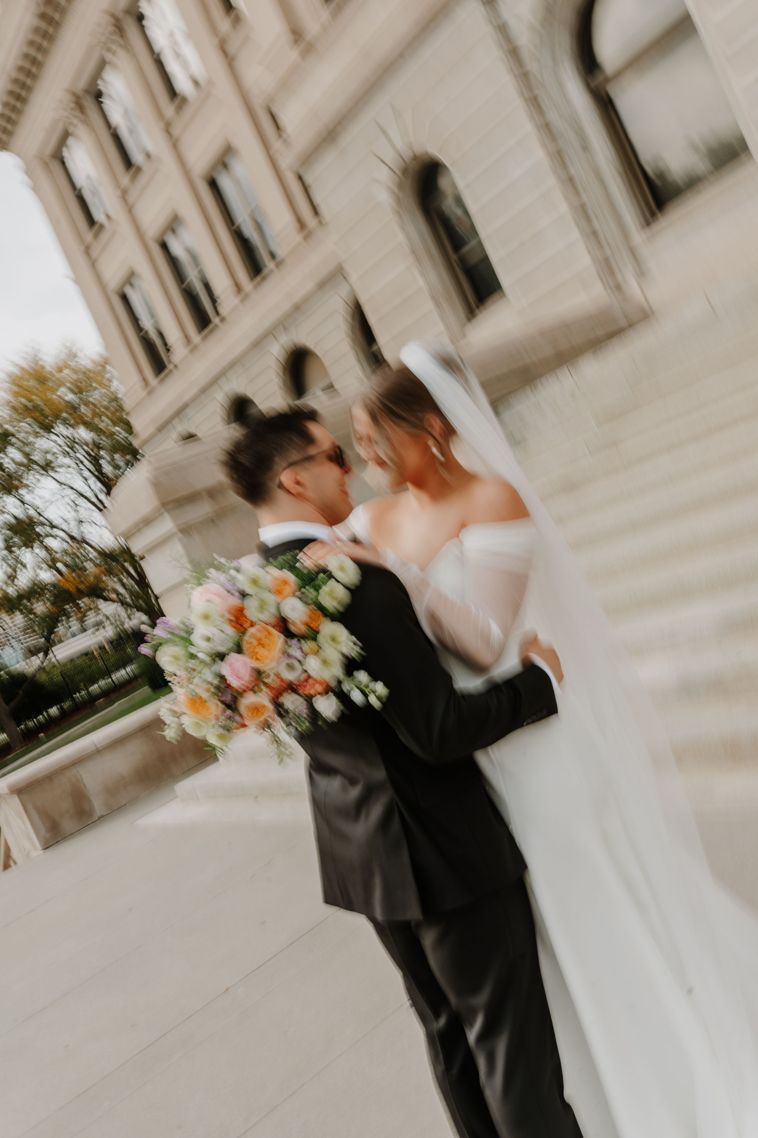 Artistic wedding photo of couple sharing romantic moment outside historic building.