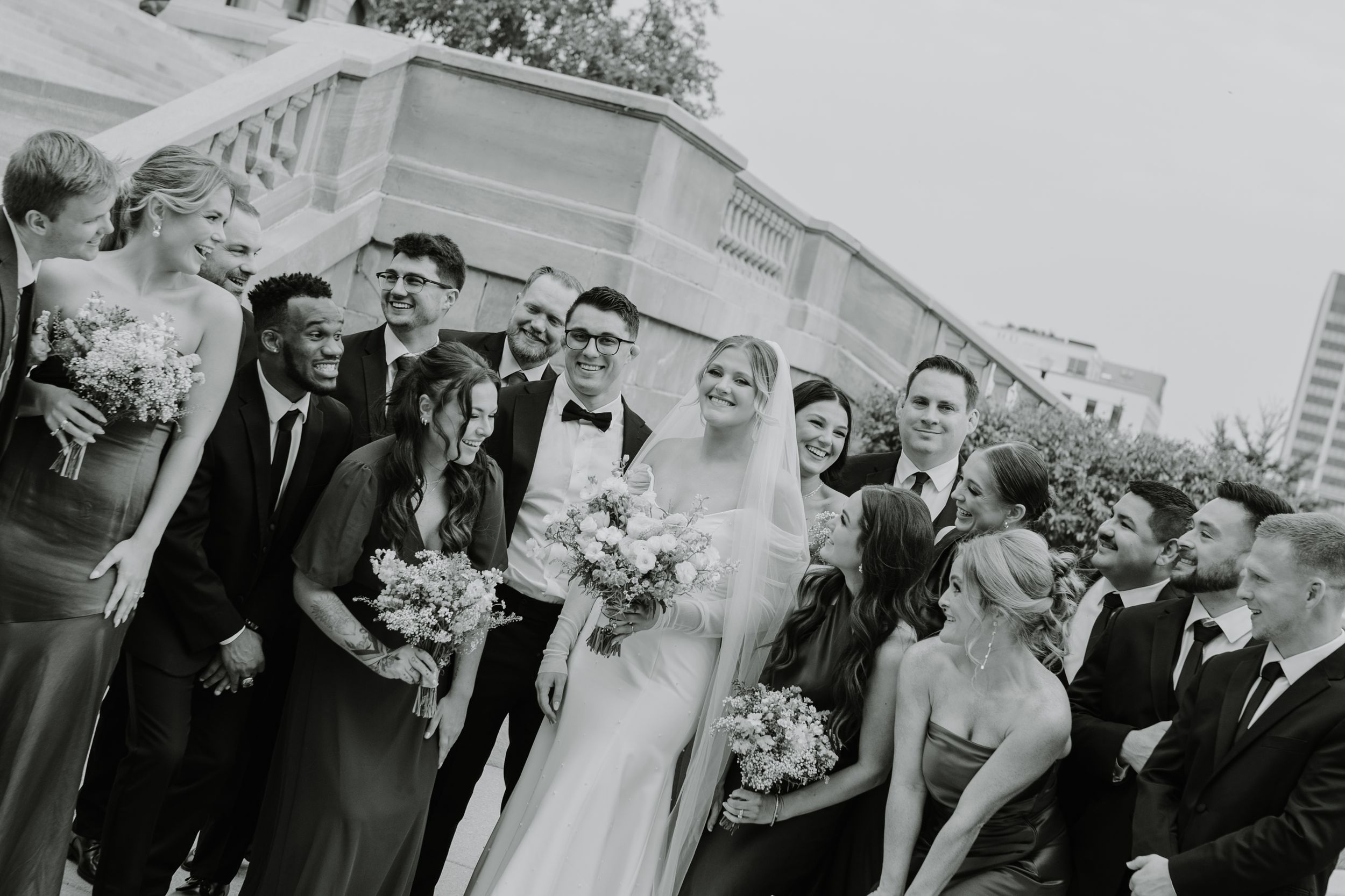 Black and white candid shot of a wedding party celebrating outdoors.