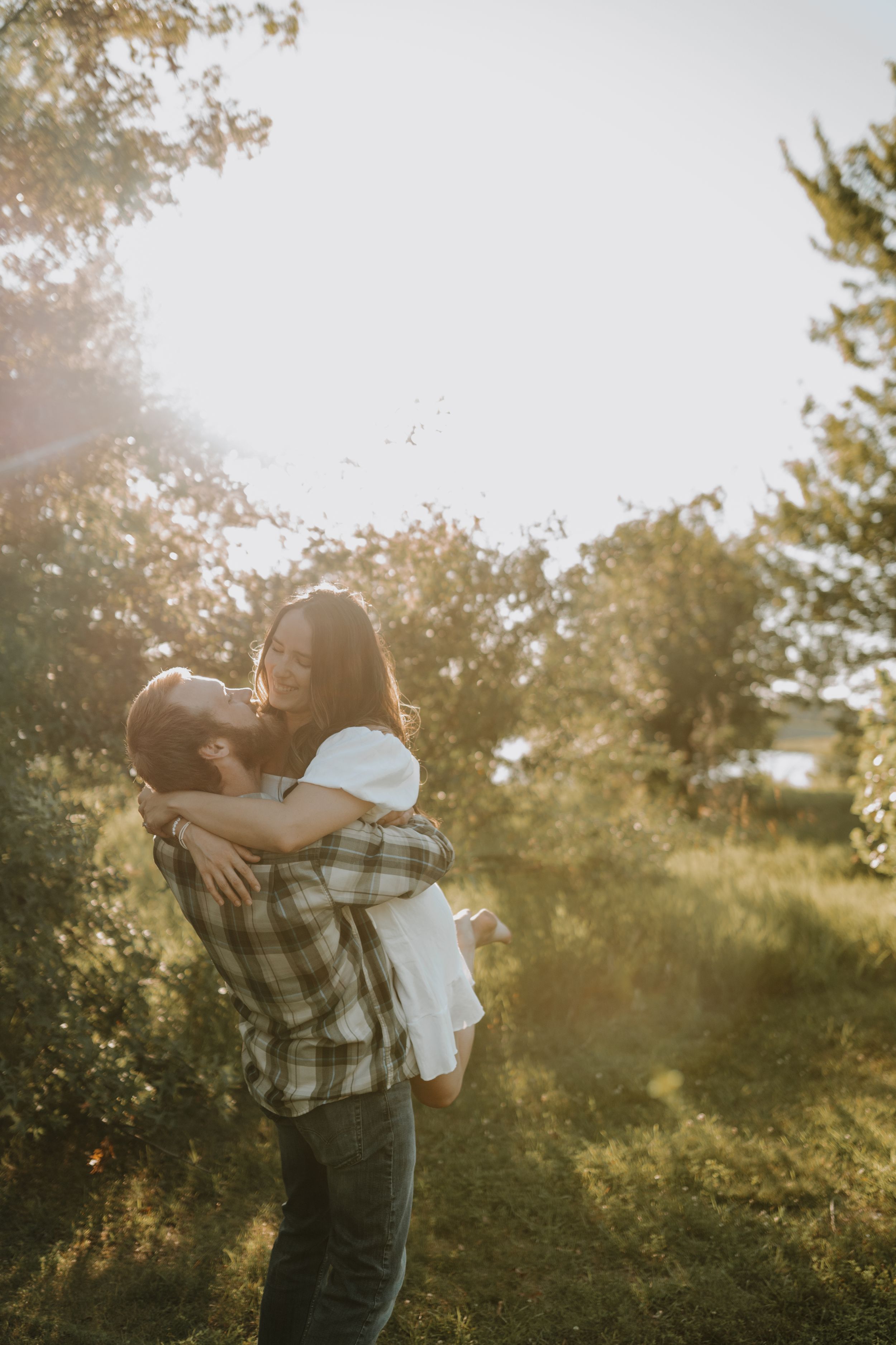 Couple sharing intimate embrace in sunlit garden setting.