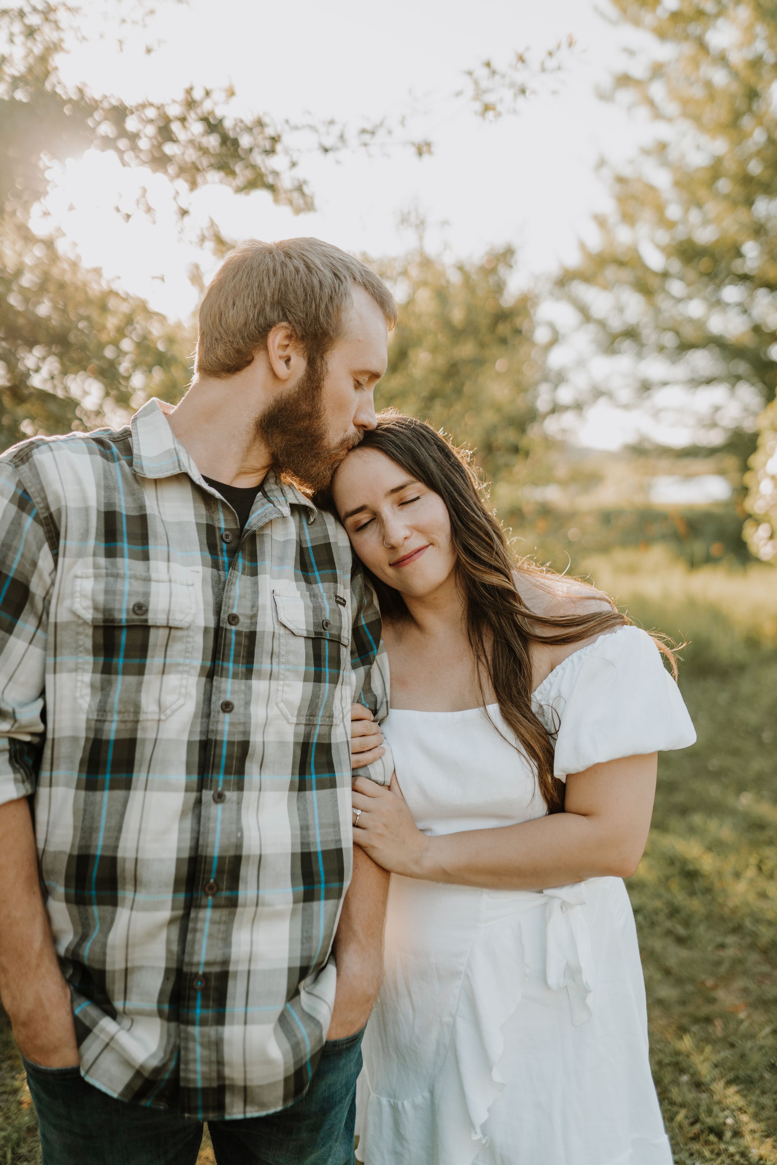 Tender moment between couple during sunset engagement session.