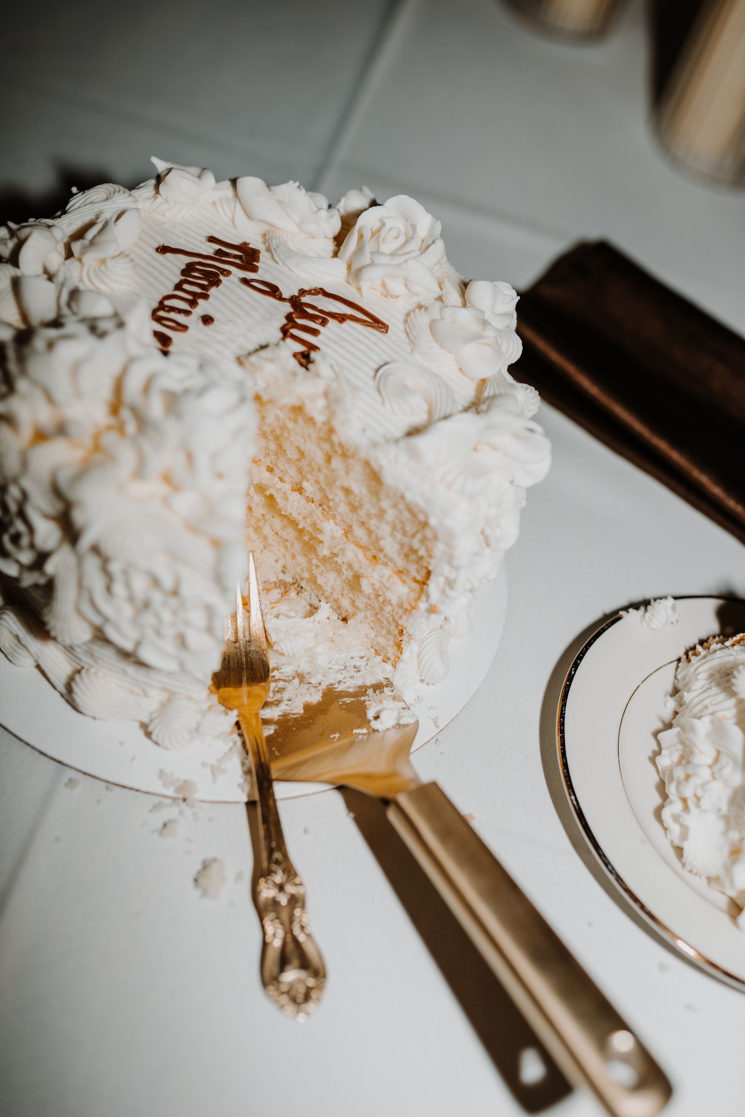 White wedding cake with detailed frosting and a slice cut out revealing golden cake inside.