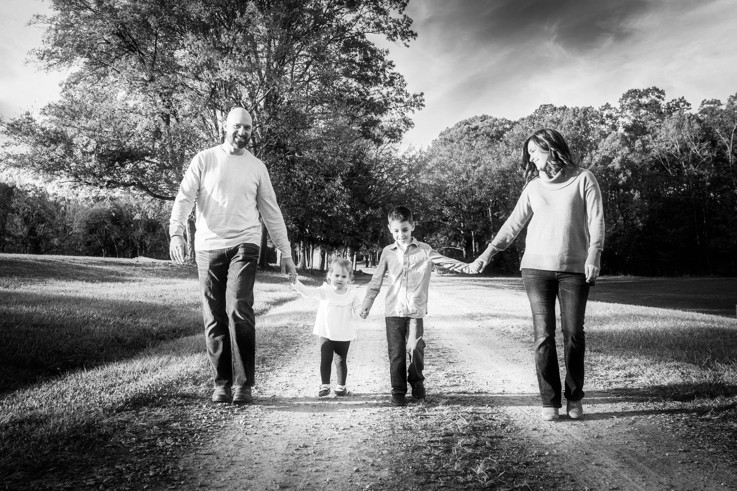 Black and white panoramic series of family walking together on a winding path.