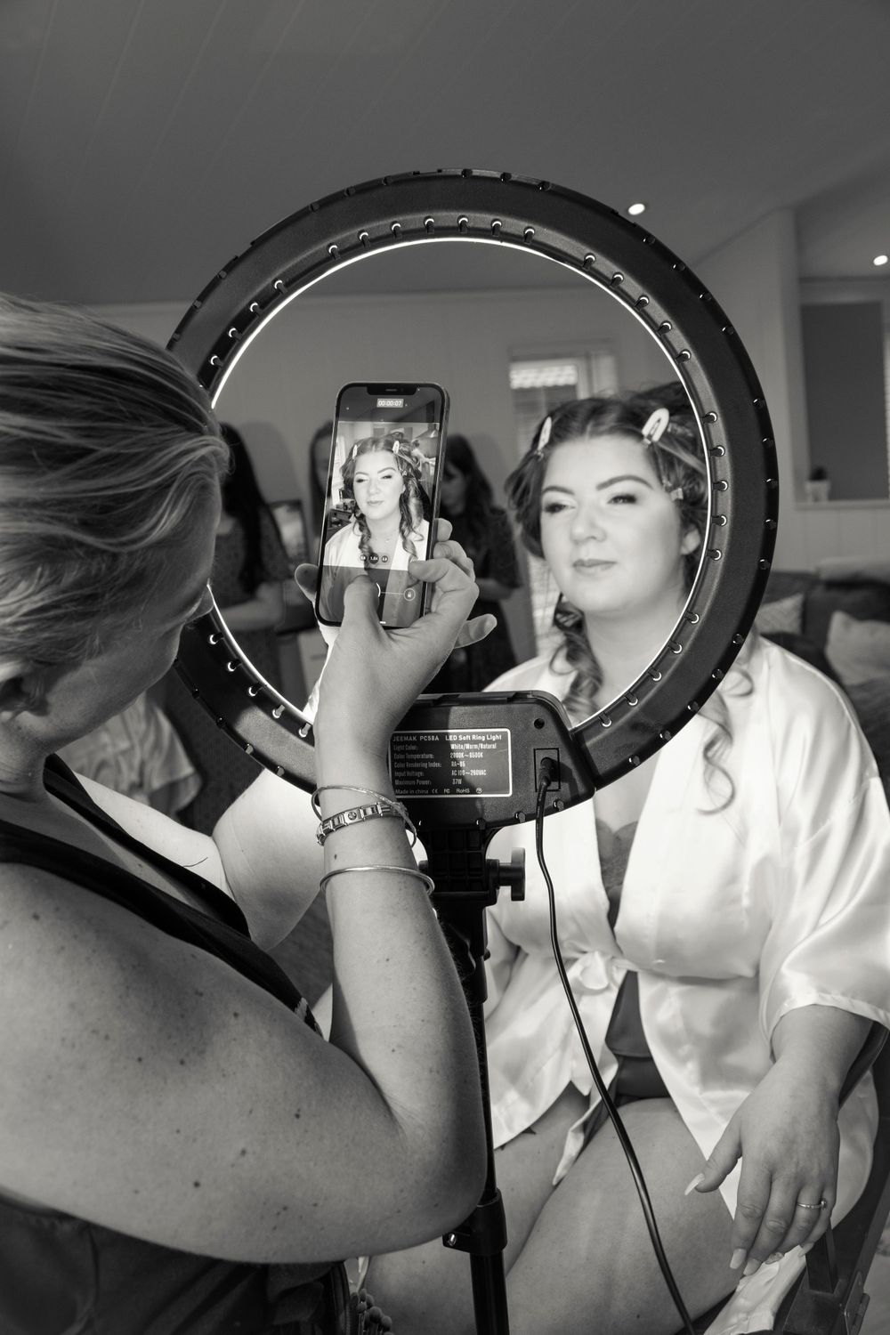 Professional makeup session captured through a ring light reflection.