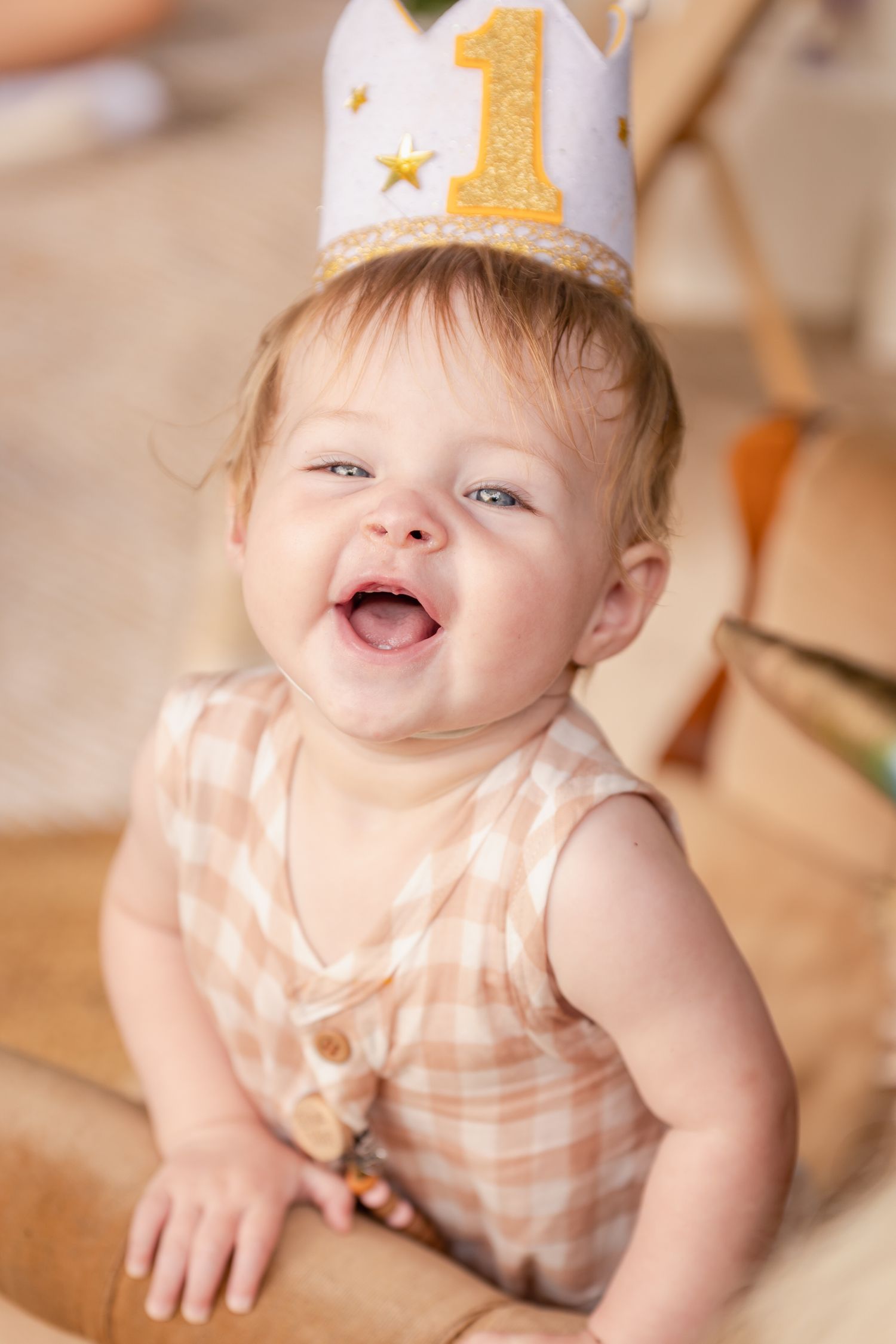 A baby wearing a gold birthday crown smiles and laughs in a series of portraits.
