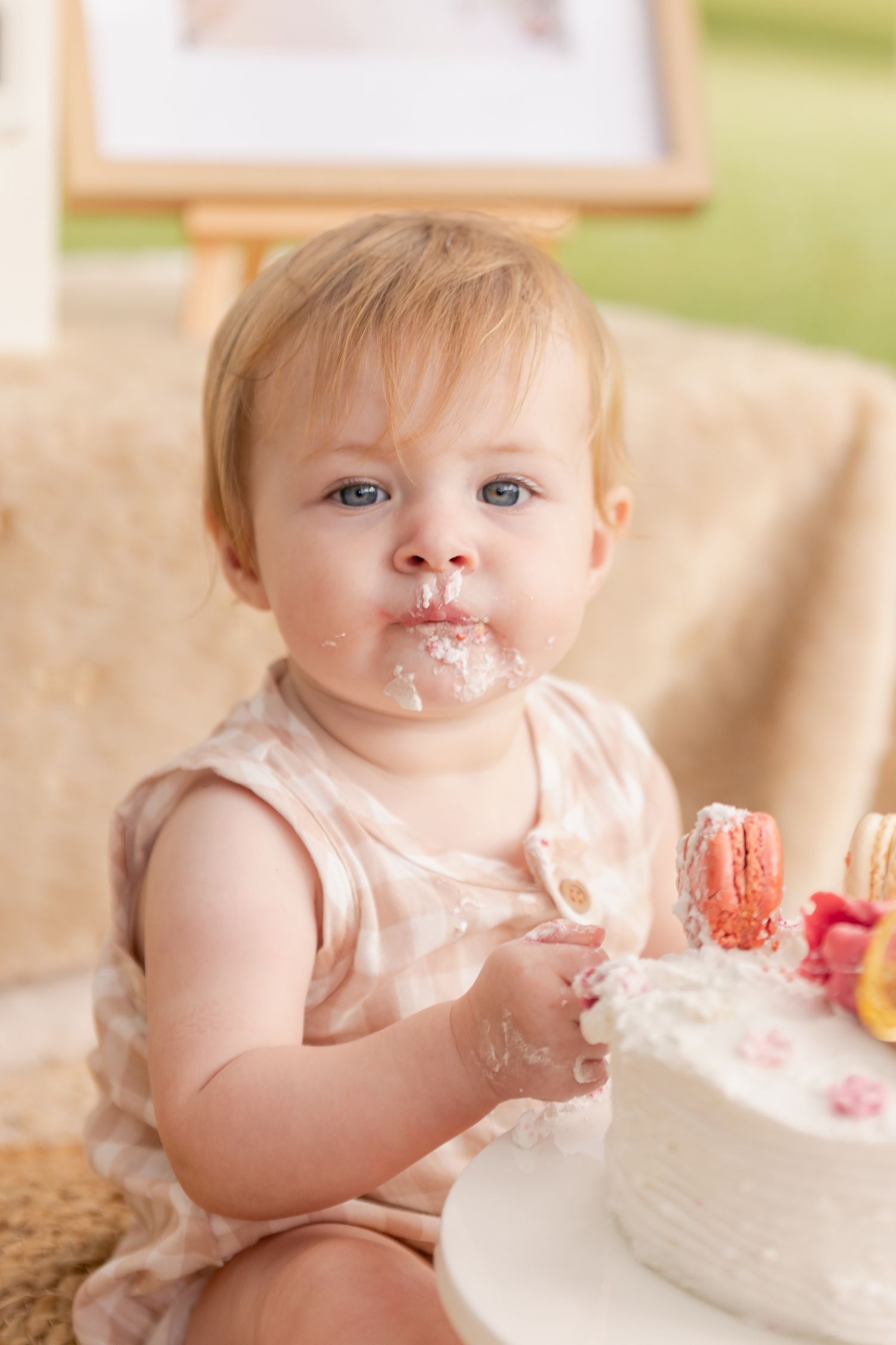 A messy first birthday cake smash photo session showing a baby covered in white frosting.