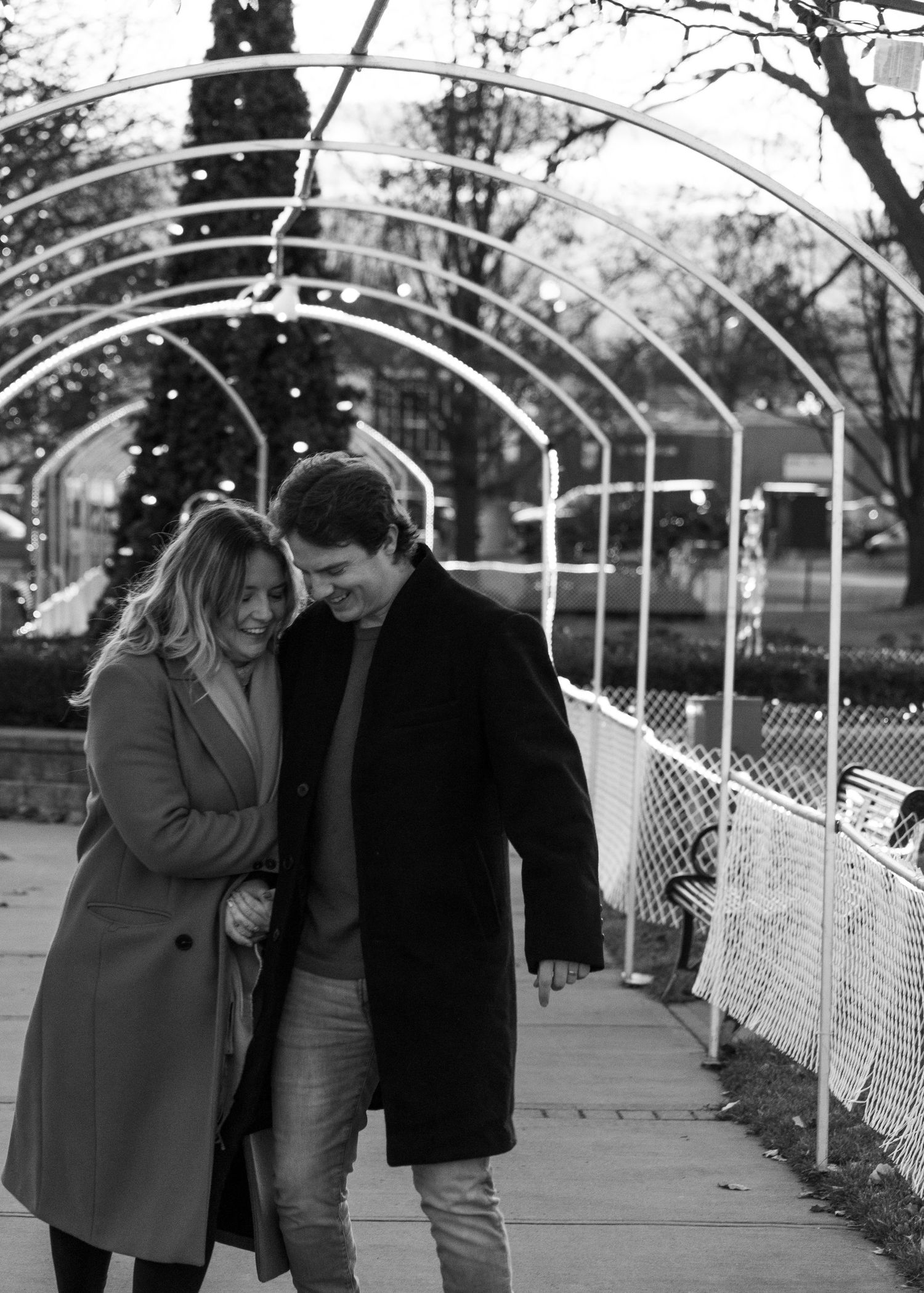 A black and white photo of a couple sharing an intimate moment under an arched walkway.