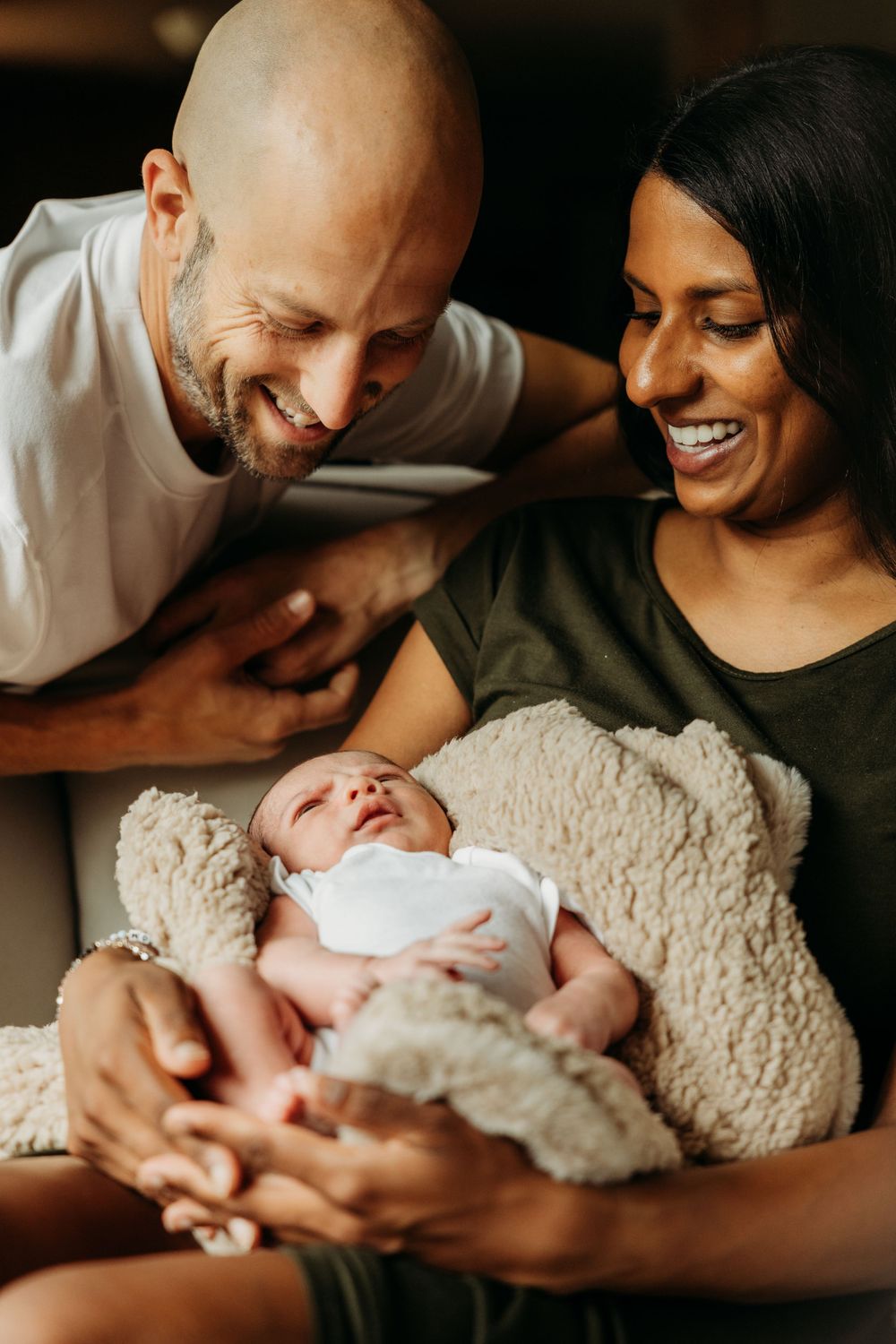 Parents sharing tender moment with newborn wrapped in cozy blanket.