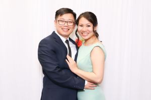 Couple in formal wear embracing against white backdrop at special event.