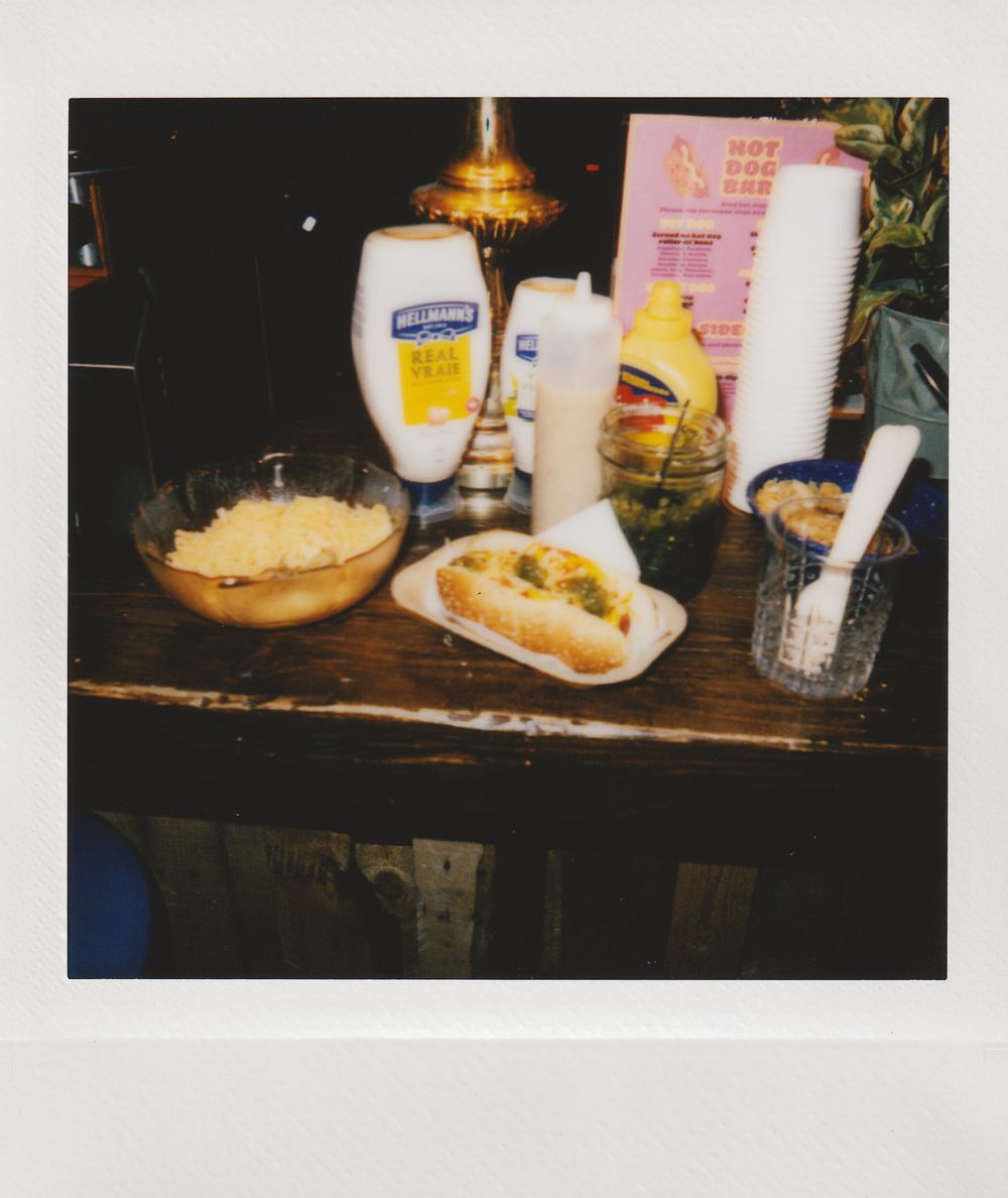 Fast food spread with condiments and hot dogs on a rustic wooden surface.