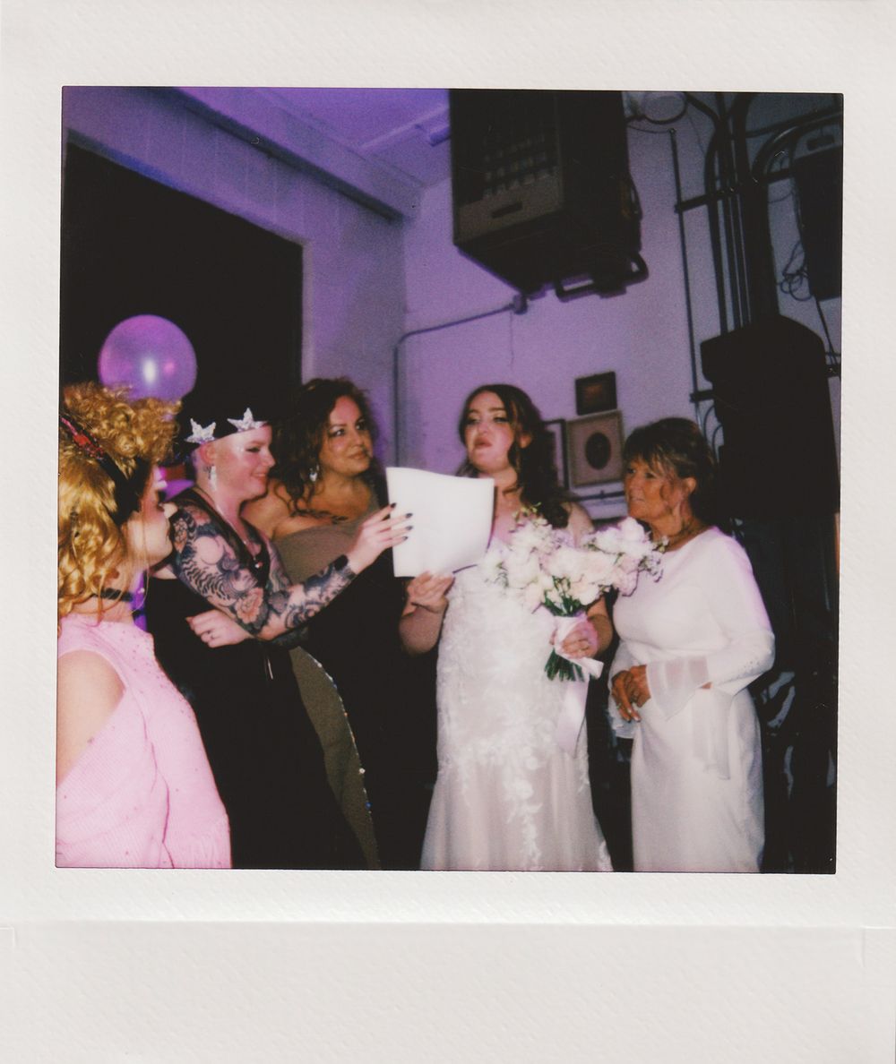 Group celebration with purple balloons and white formal attire.