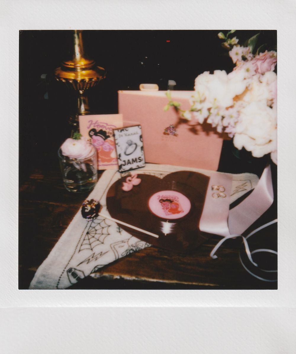 Record player on dark wood table with pink decor and candlelight creating romantic ambiance.