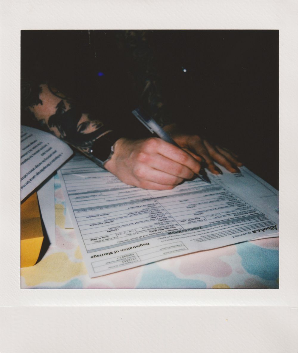 Close-up of hands filling out paperwork form under low lighting.