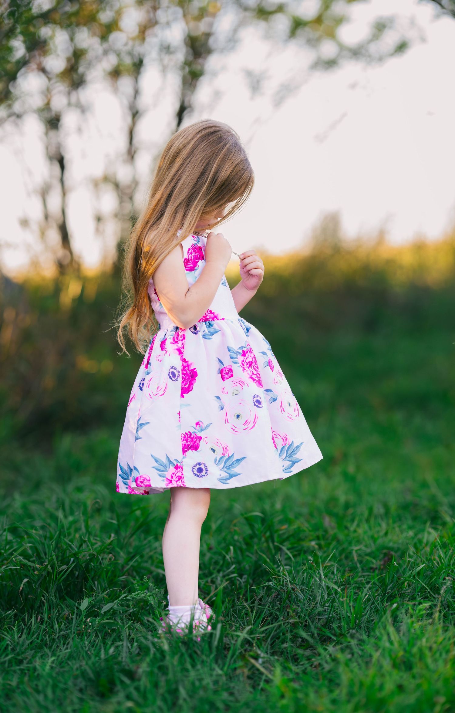 Floral summer dress twirls in a sunny garden setting.