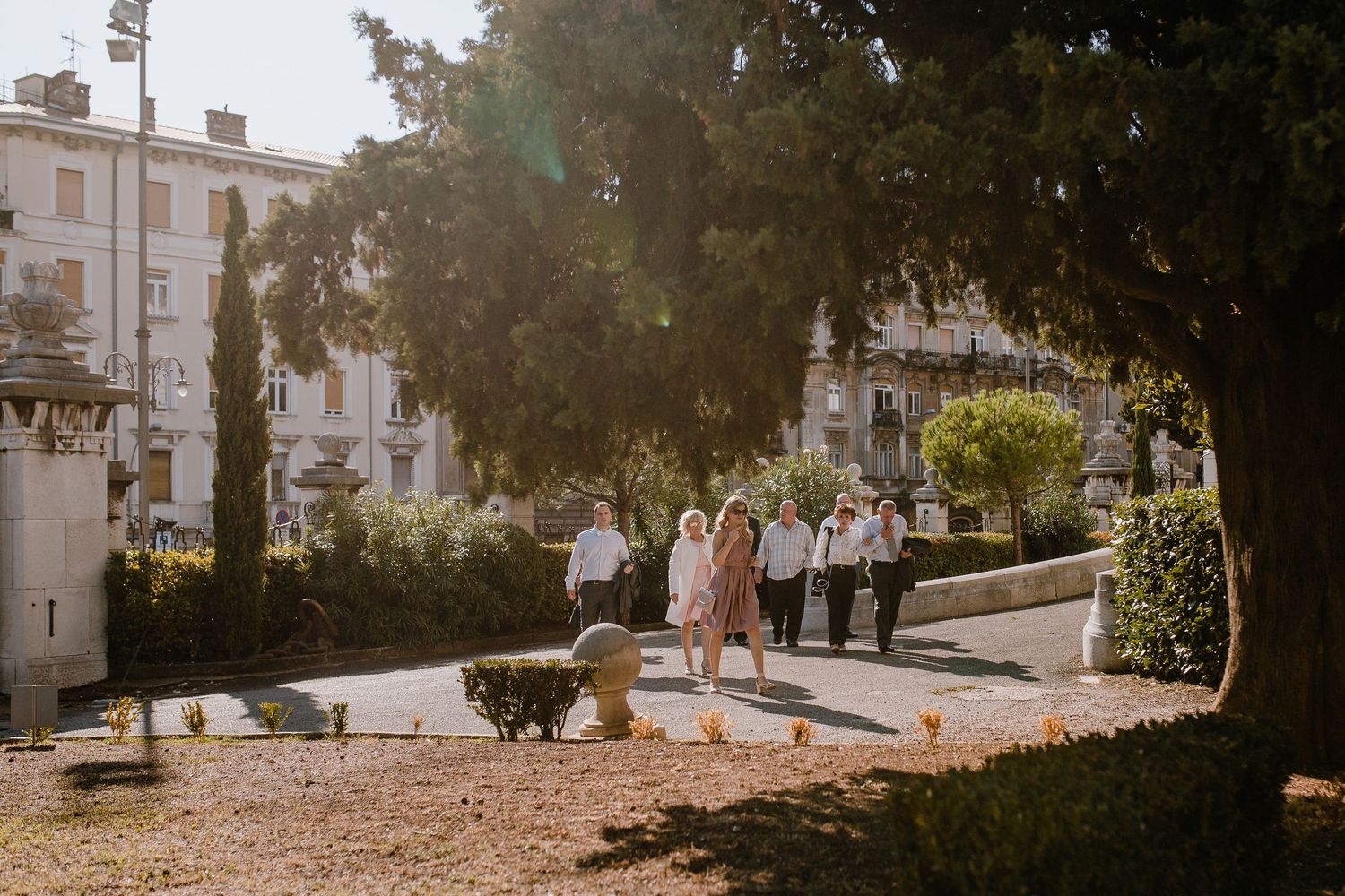 Wide shot of wedding guests, backlit by the soft glow of the setting sun, creating a warm and inviting atmosphere.