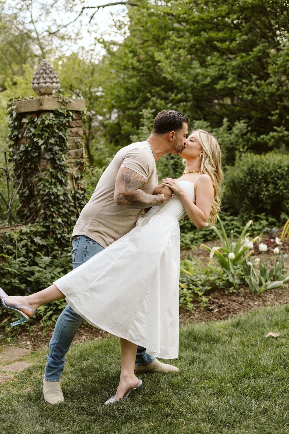 A romantic dance pose in a lush garden setting with ivy and greenery.