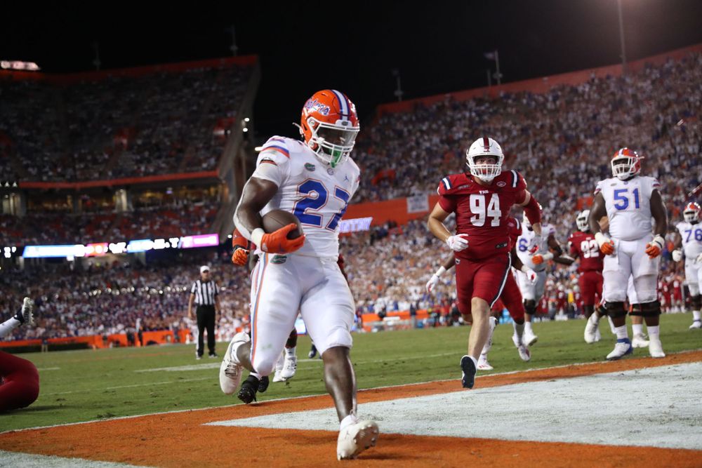 Football player running with the ball during a night game at stadium.