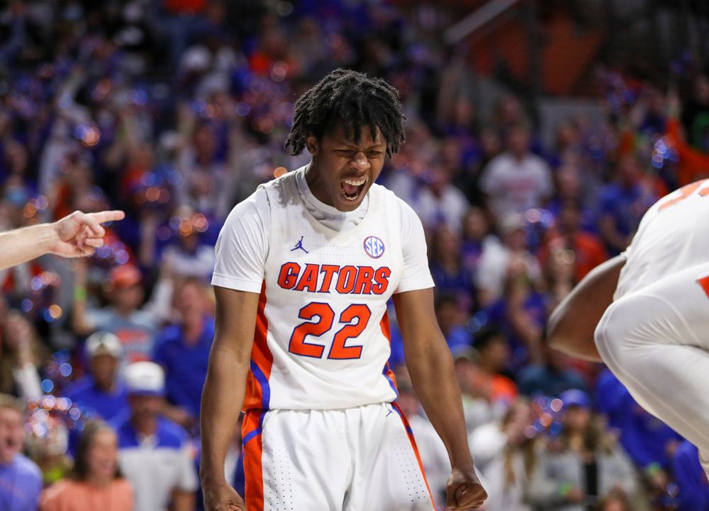 Basketball player in white Gators uniform during an intense game moment.