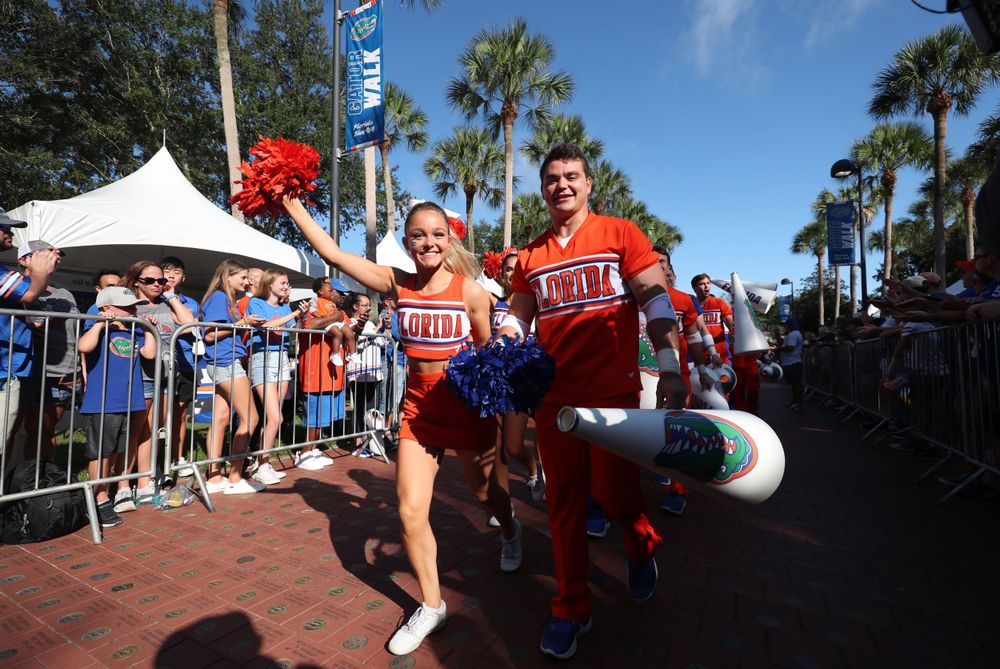 College cheerleaders in blue and red uniforms pose during a spirited outdoor event.