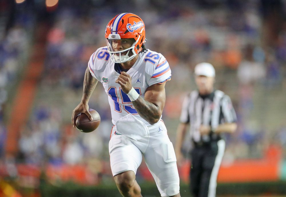 Football player in white and orange uniform runs with ball during game action.