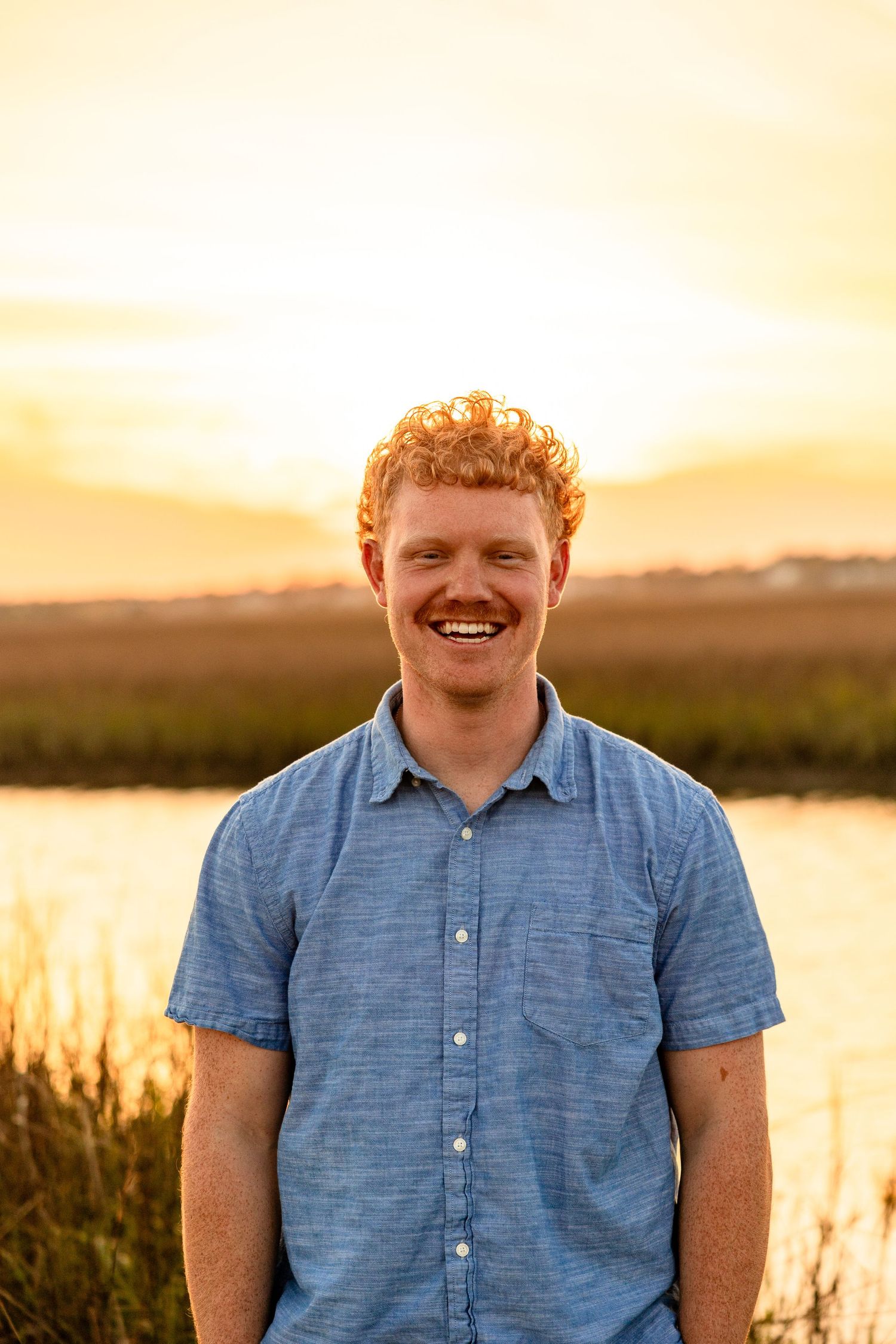 A young man smiling for a photo on the Wrightsville Beach coast