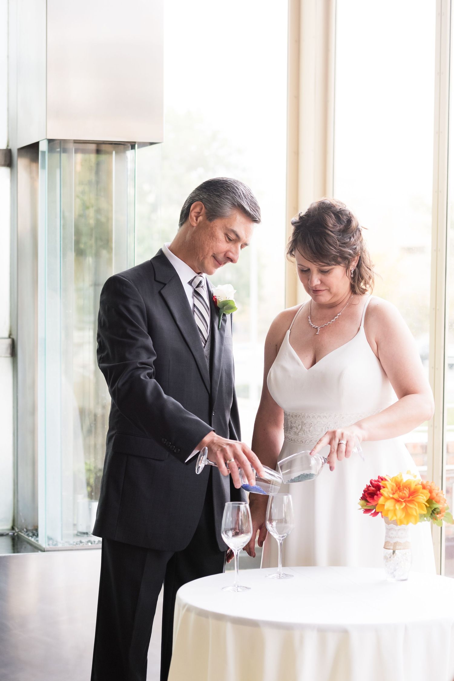 A couple admires their wedding rings while standing next to a reception table.