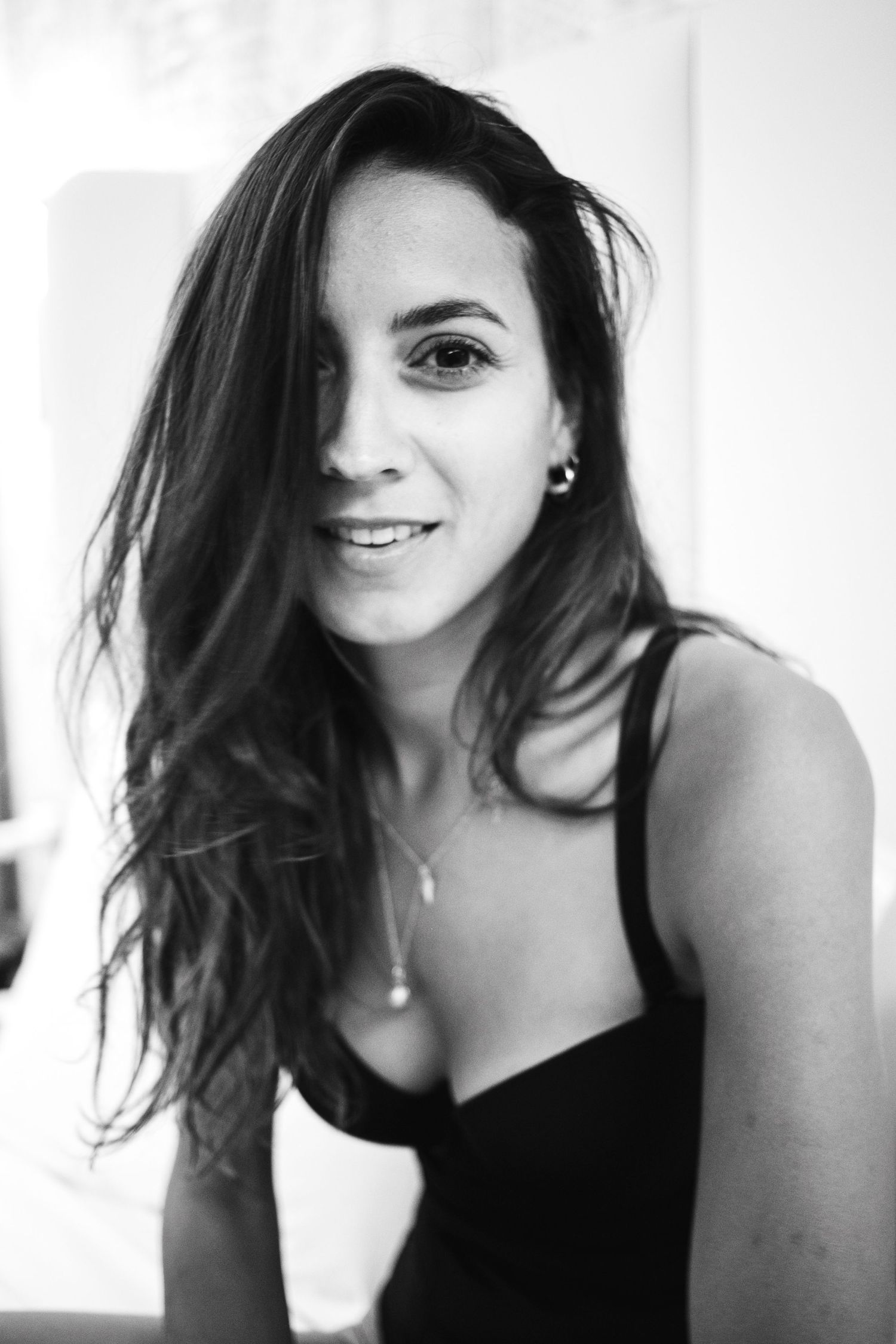 Black and white portrait of someone with long dark hair and a black top smiling at the camera.