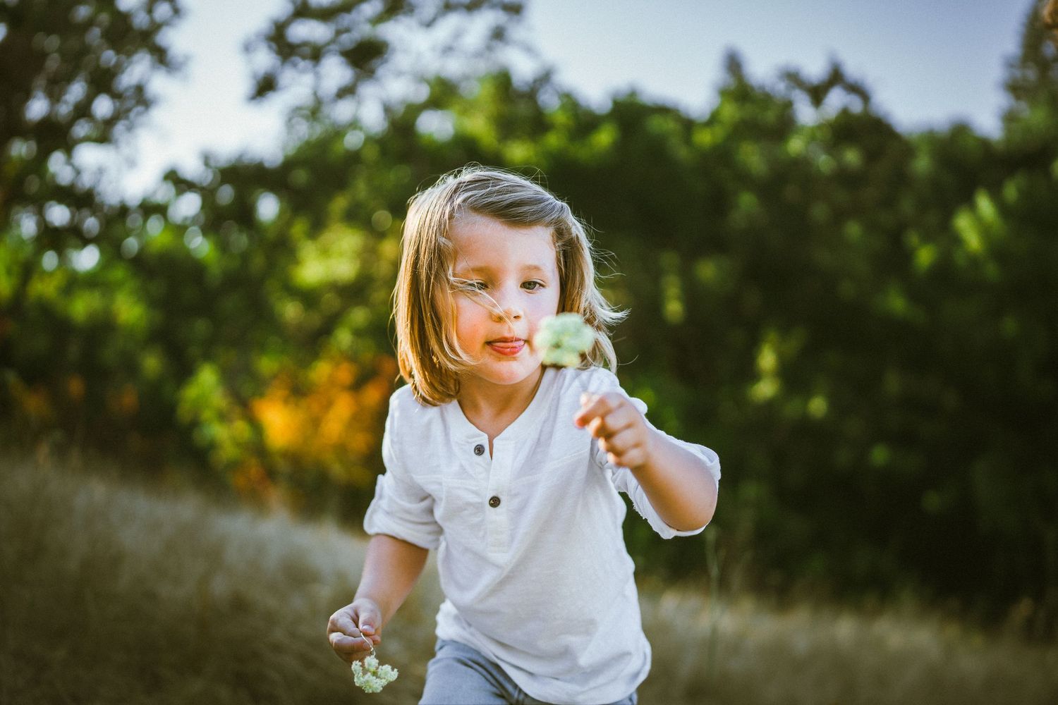 Natural outdoor family portraits taken in a sunlit garden setting.