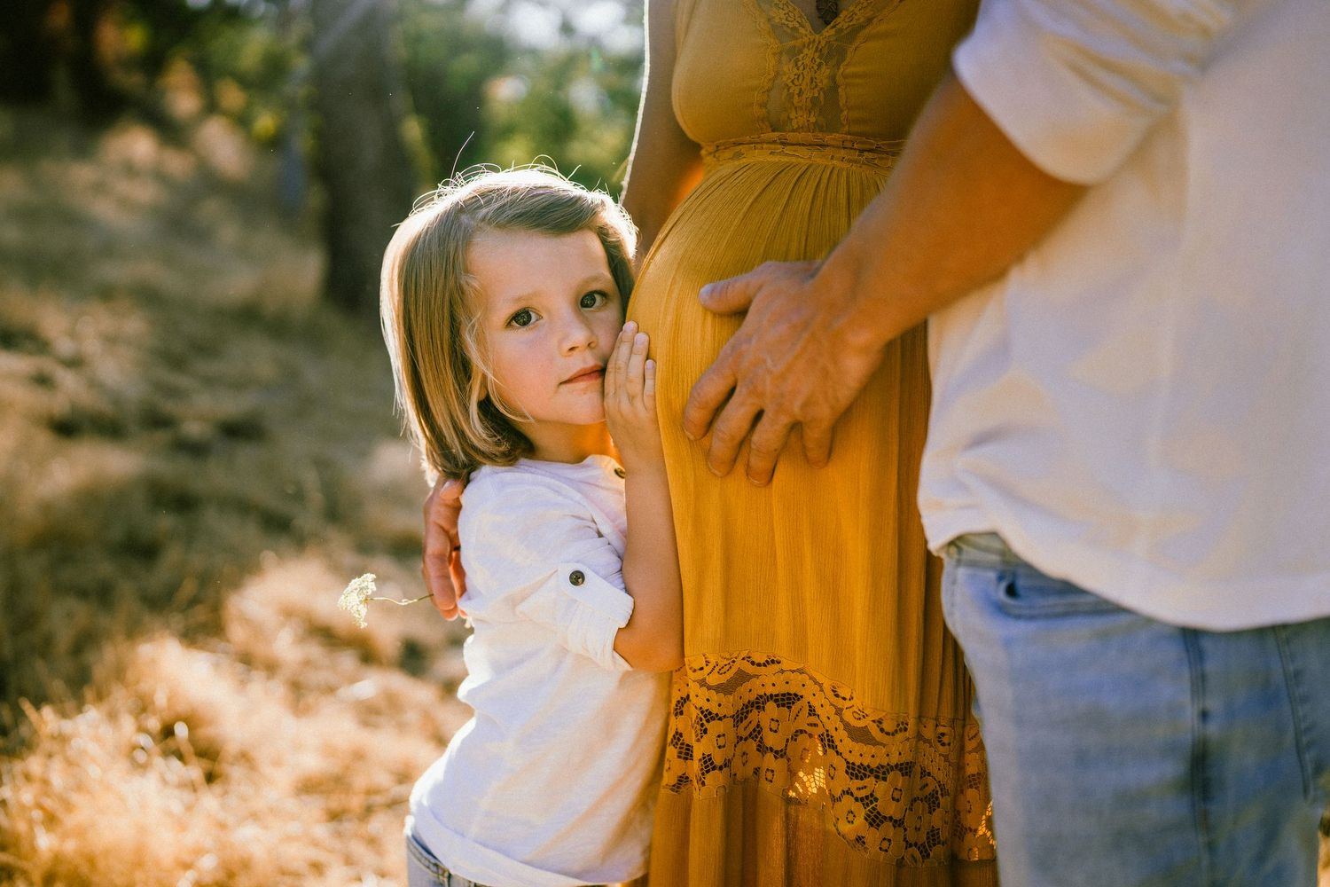 Close-up shot of a family maternity photo session with warm golden light filtering through.