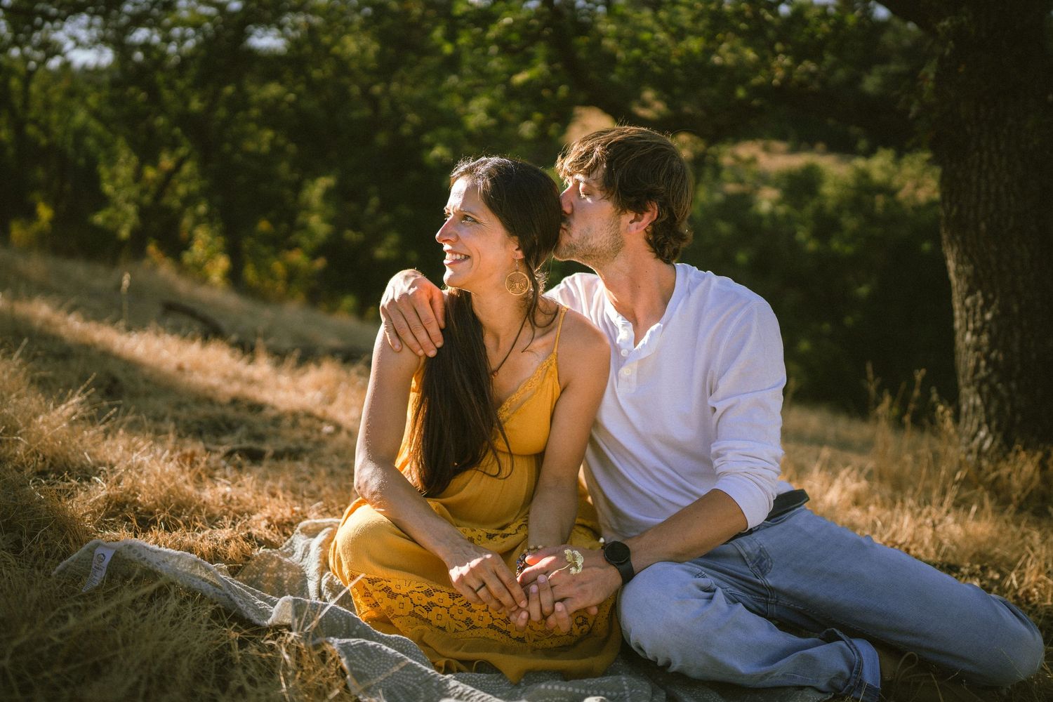 Candid family moments captured on a grassy hillside during sunset.
