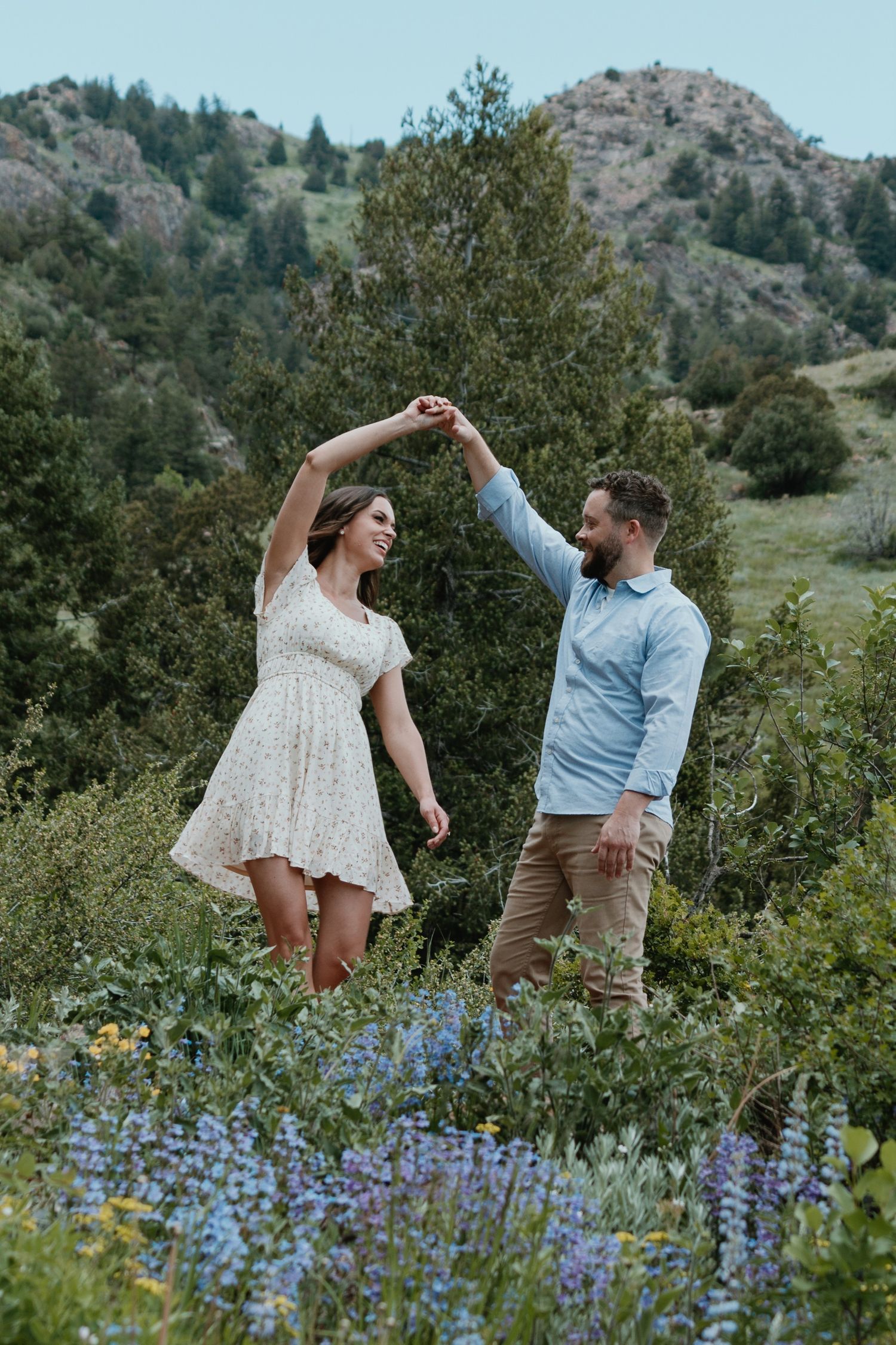 A couple dancing together in a mountain meadow filled with purple wildflowers.