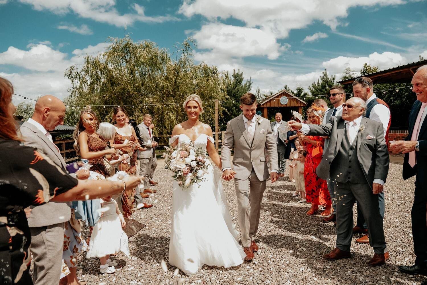 The bride and groom joyfully walk down the aisle after their wedding ceremony, surrounded by guests tossing petals