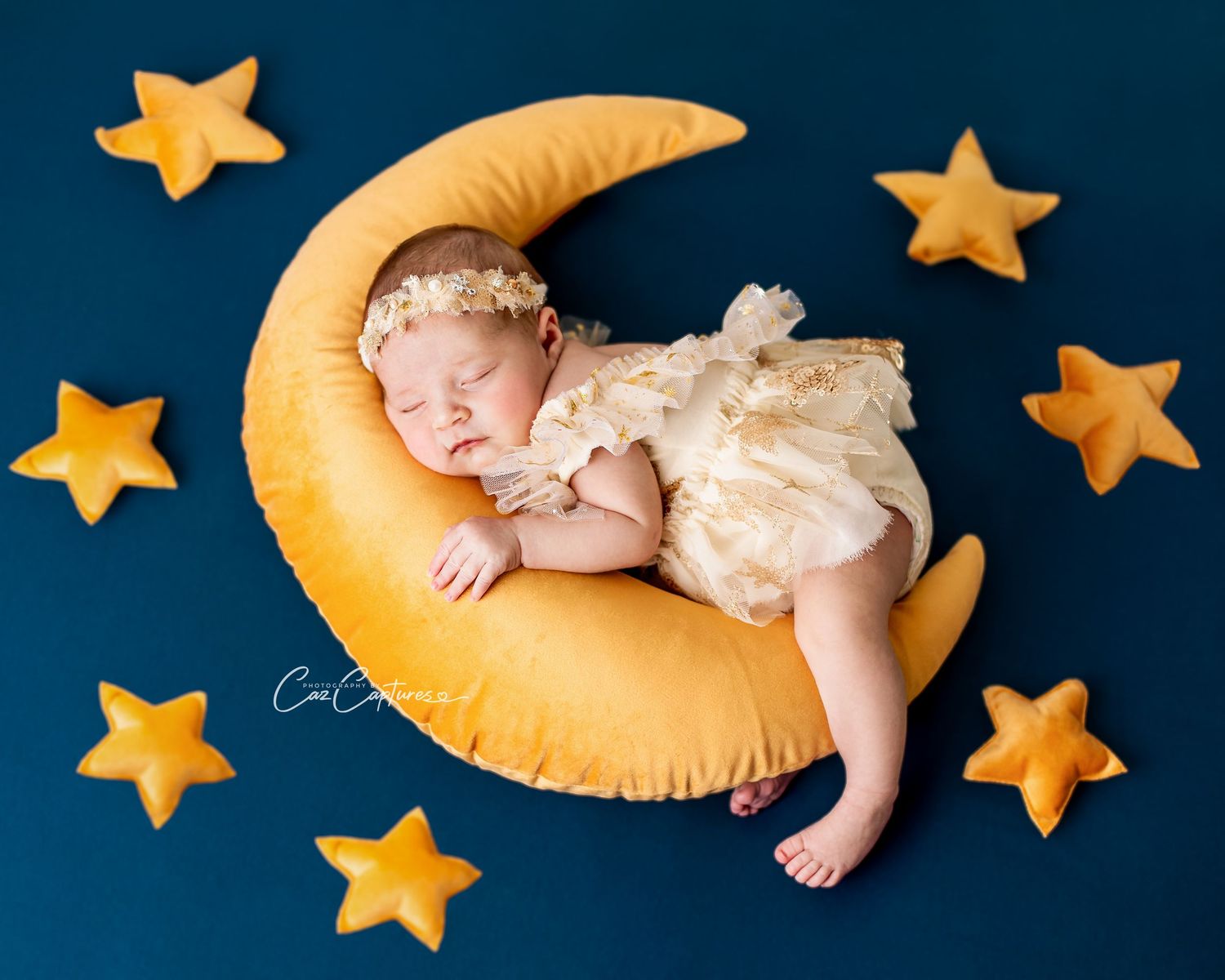 Newborn portrait of newborn girl cuddling a moon on a star filled sky, taken at Caz Capture Sydney photography studio.