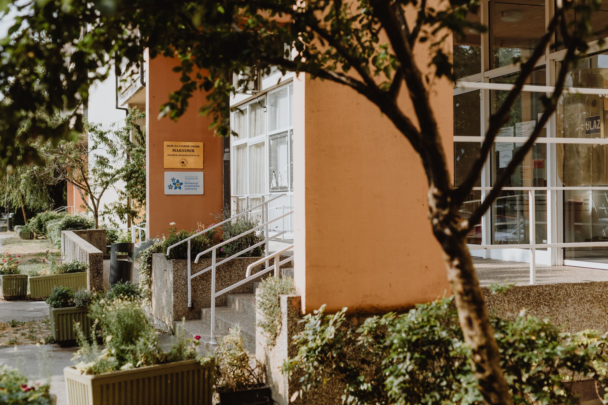 Close-up of the main entrance to a senior home, featuring accessible pathways and gardens.