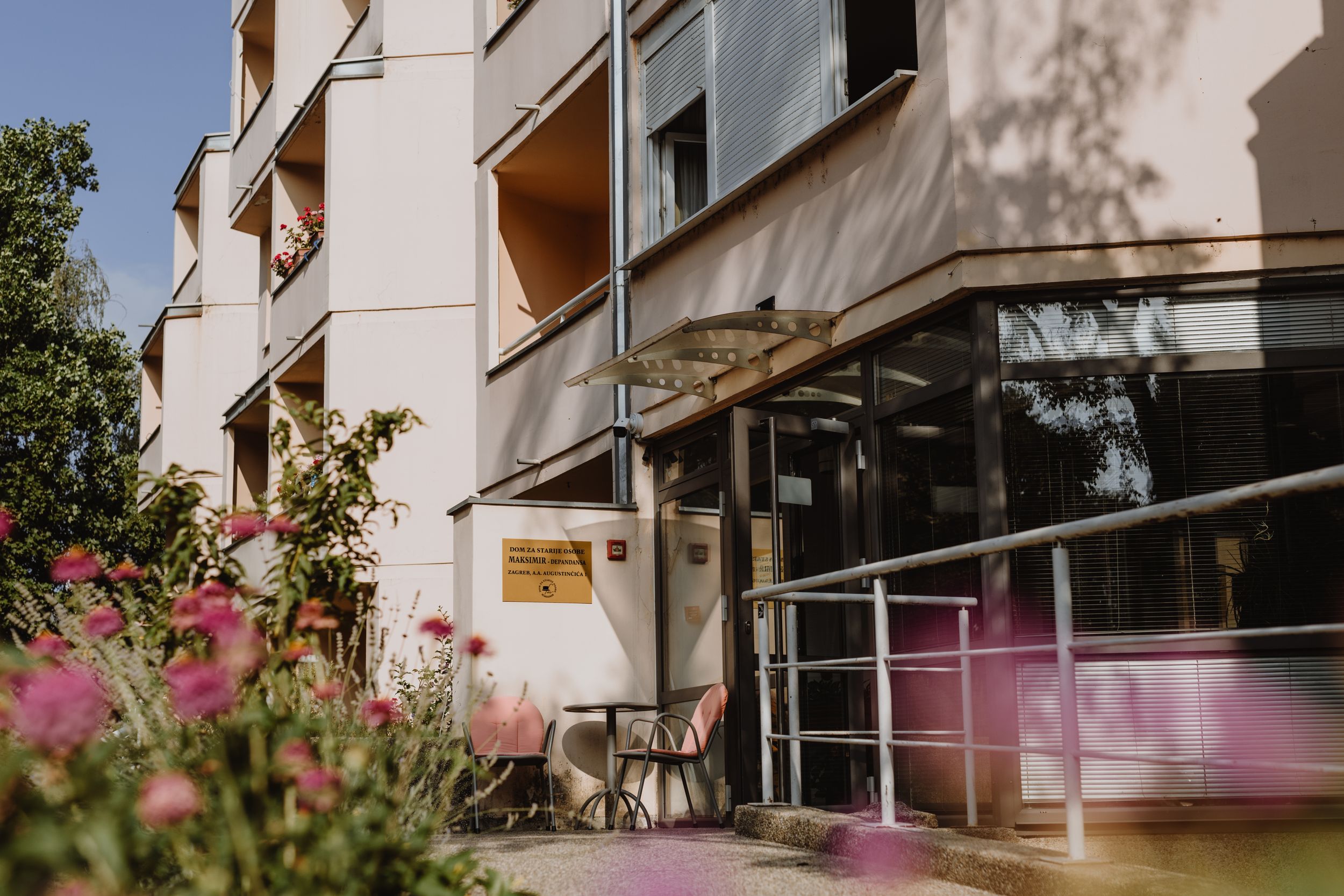 Prikaz glavnog ulaza u dom za starije osobe, s pristupačnim putevima i vrtovima u stilu brend fotografije..