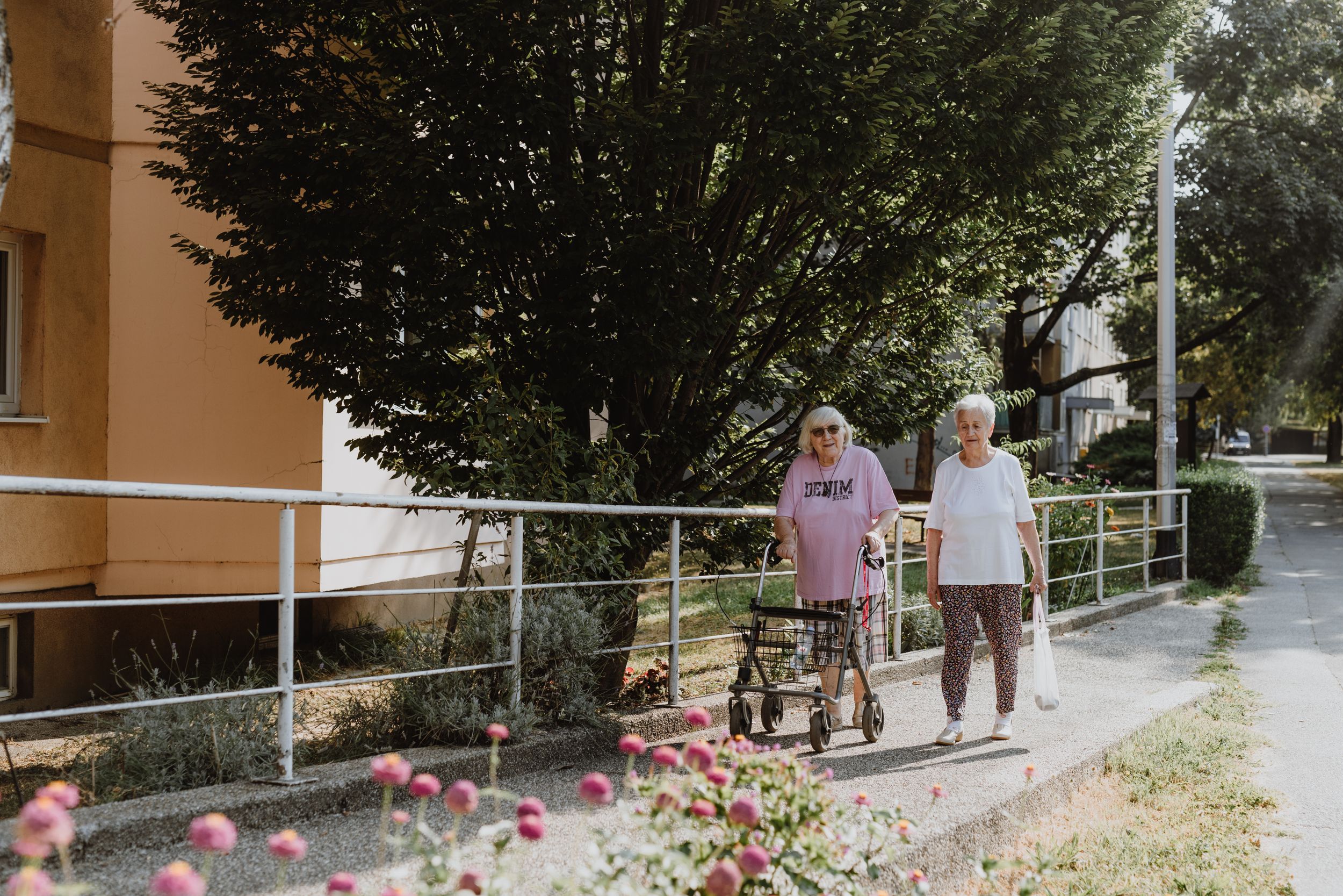 Eksterijer doma za starije osobe fotografiran u stilu komercijalne fototografije, s zelenim površinama i šetnicama.