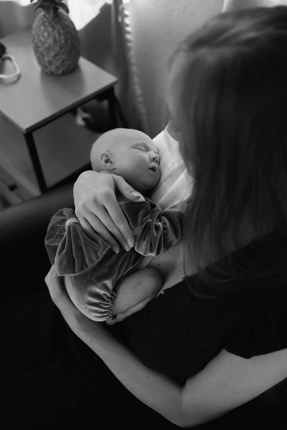 Black and white photo series showing tender moment between a parent and newborn baby.  Baby is lay on mothers chest, birds eye view shot