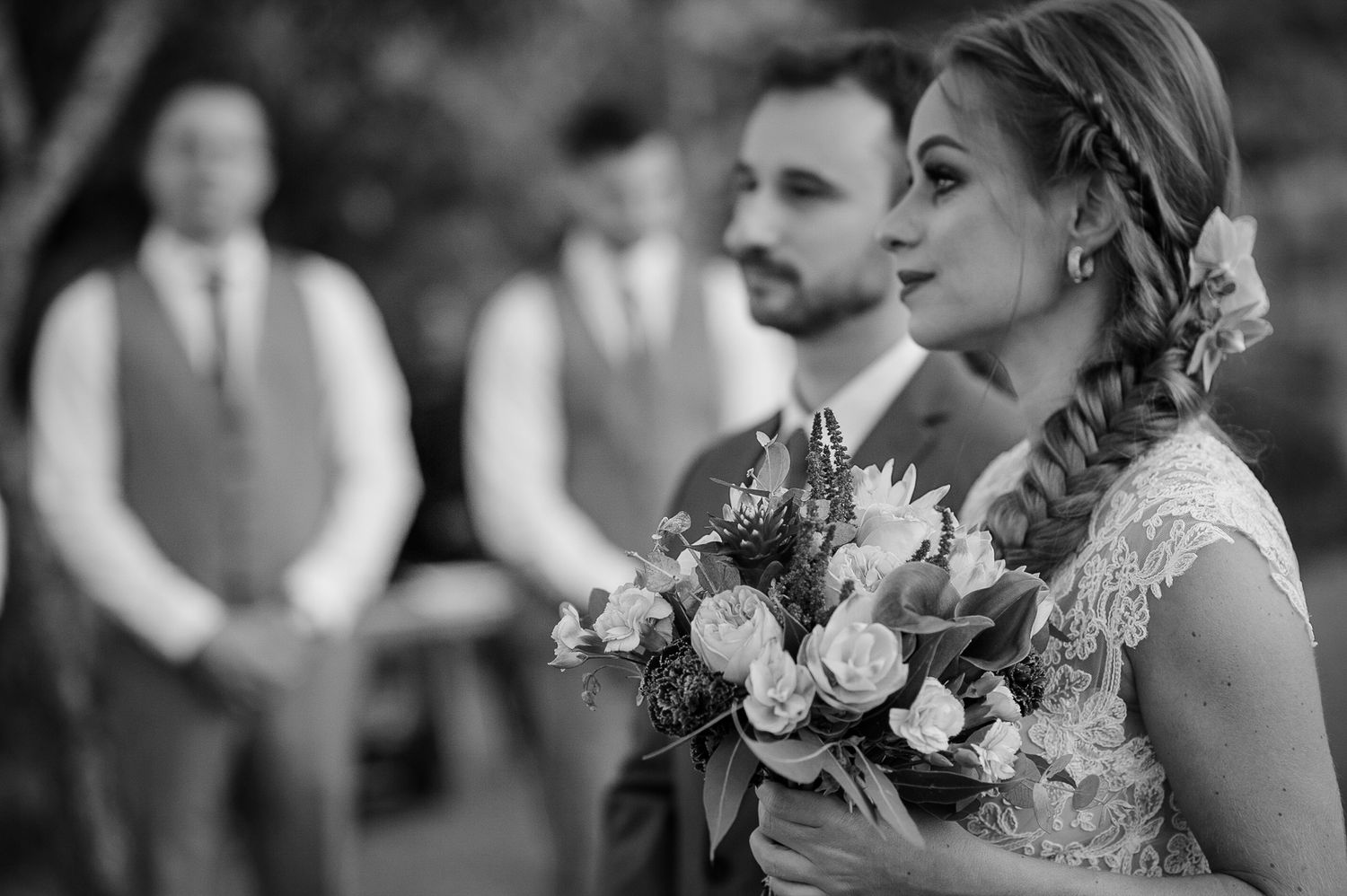 Black and white portrait of a wedding ceremony moment with floral bouquet.