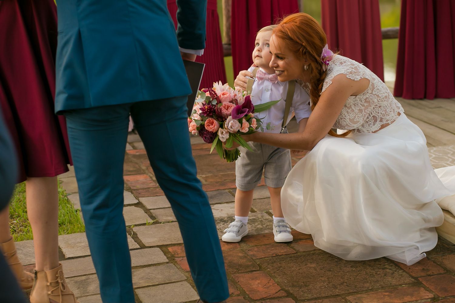 Candid wedding moment with bouquet of pink flowers on brick patio.