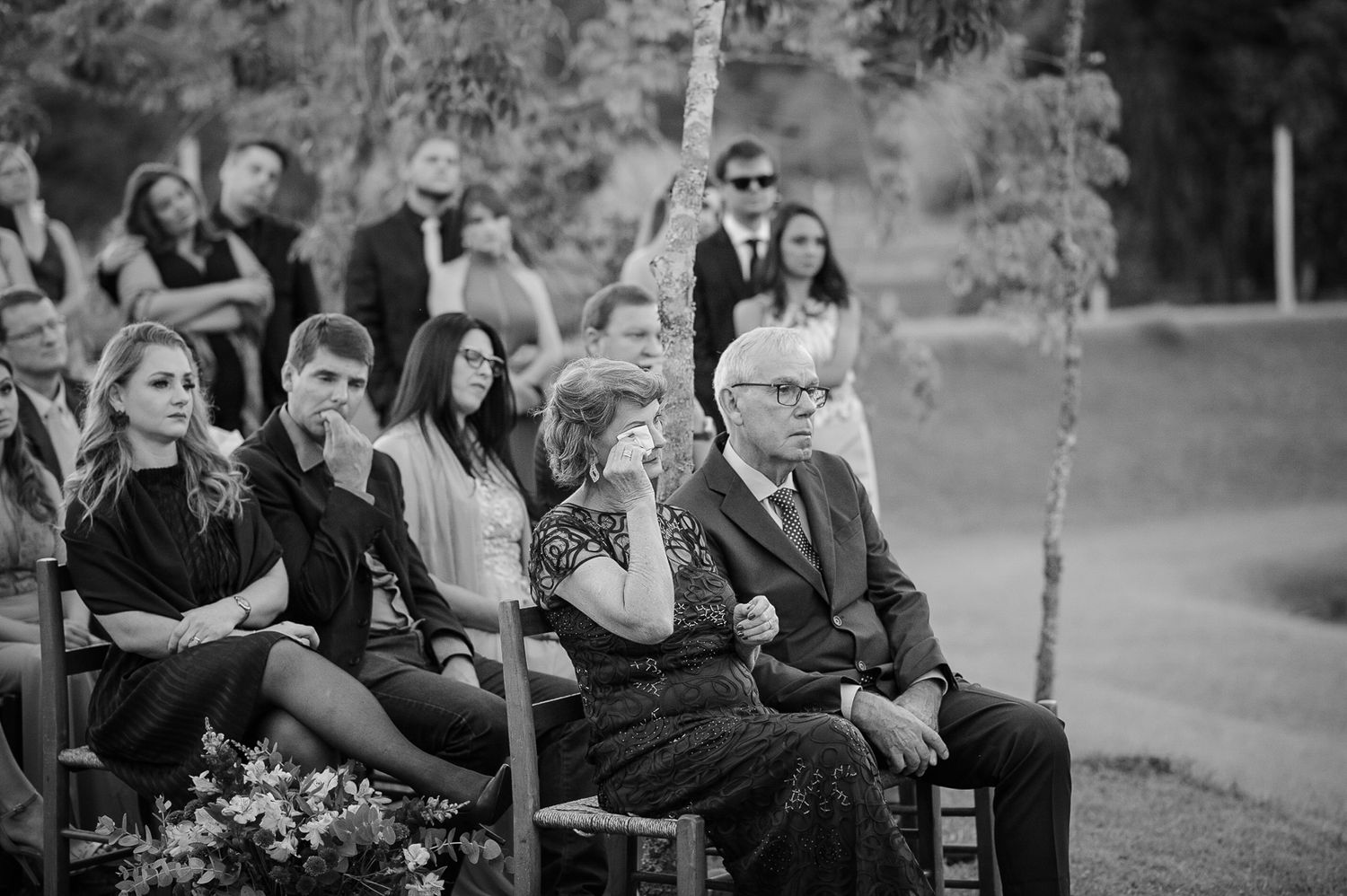 Black and white photo of wedding guests seated during outdoor ceremony.