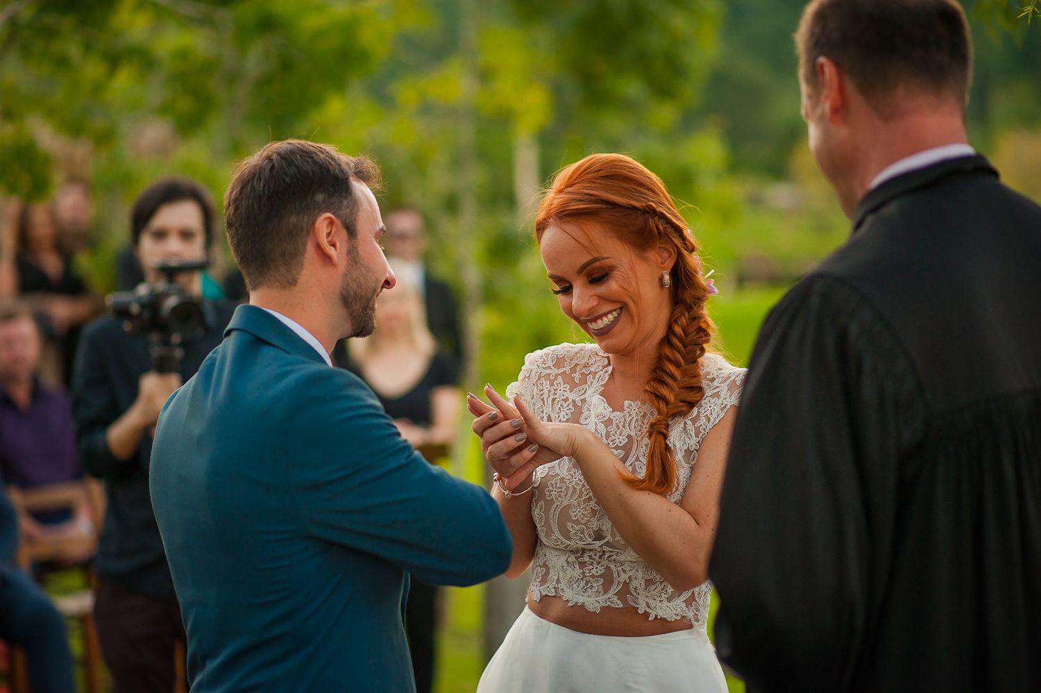 A couple shares a lighthearted moment during their wedding vow exchange outdoors.